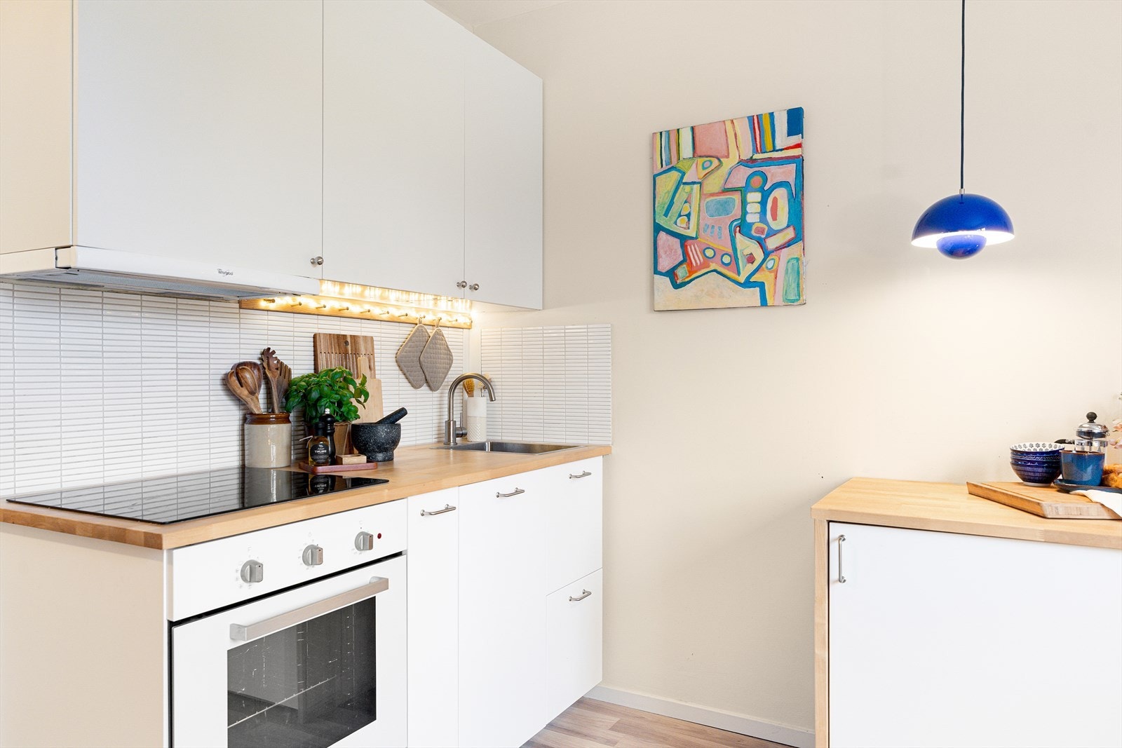 Innredningen har glatte, laminerte fronter, kum med ettgreps blandebatteri og fliser mellom overskap og benkeplate. Galleribilde