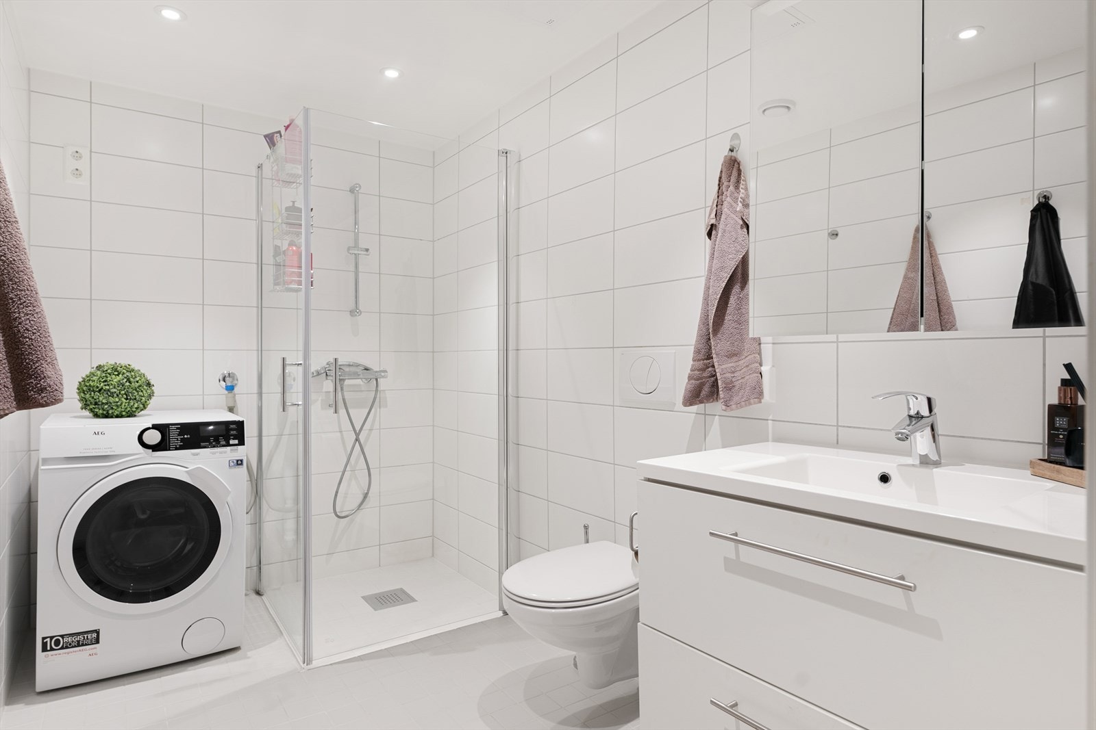 Moderne, helfliset bad med servantinnredning, vegghengt toalett og dusjhjørne. Galleribilde