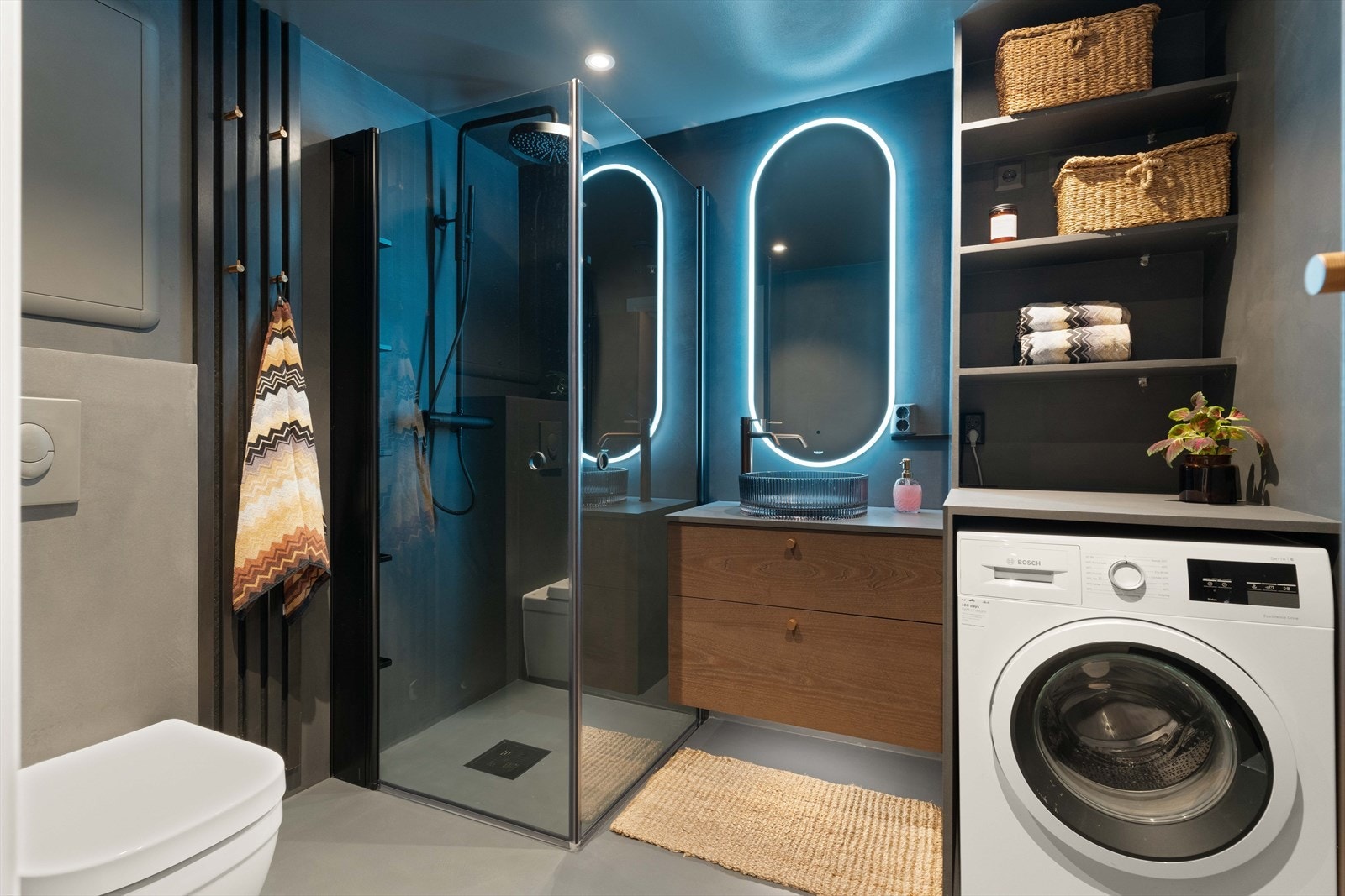 Lekre og praktiske detaljer med spiler med knagger, og hyller for oppbevaring, samt benk for enkel bretting av klær over vaskemaskinen. Her inne får du en god start på dagen! Galleribilde