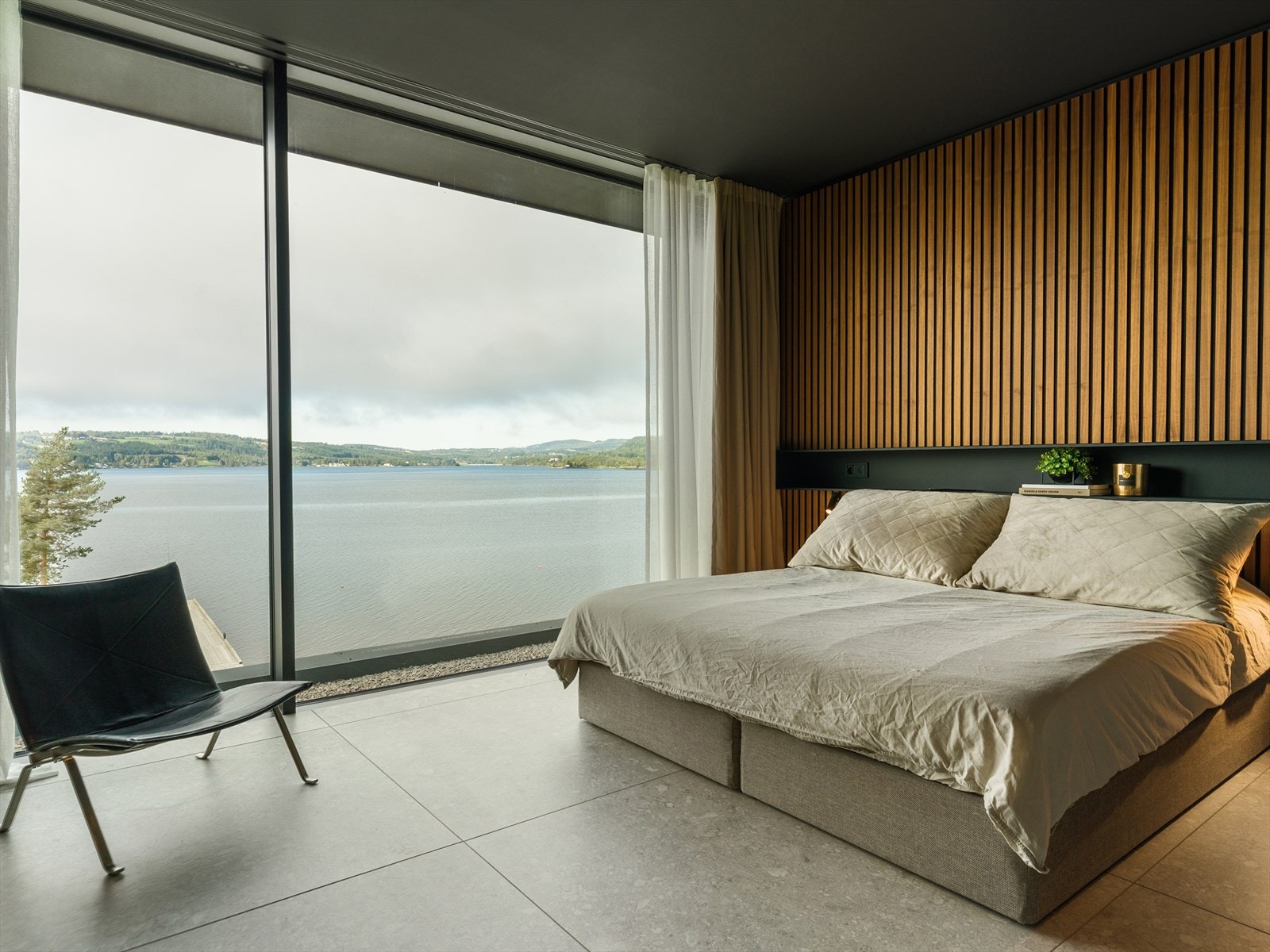 Et rom for ro og raffinement - Med panoramautsikt mot Mjøsa, helglass mot badet og plassbygde detaljer i naturlige materialer, fremstår hovedsoverommet som en privat suite med hotellfølelse og arkitektonisk presisjon. Galleribilde