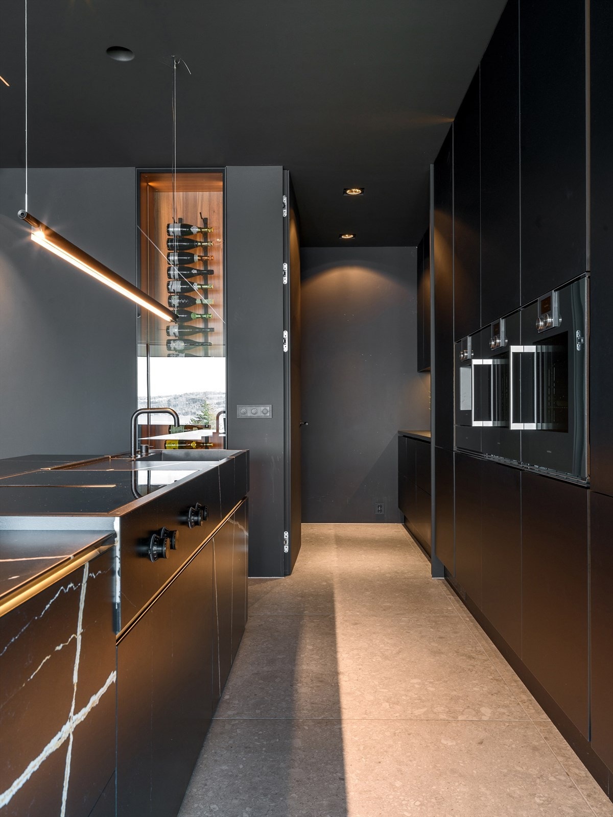 Innenfor hovedkjøkkenet ligger et diskret grovkjøkken med to oppvaskmaskiner og fryseskap, perfekt for matforberedelser og skjulte funksjoner i hverdagen. Galleribilde