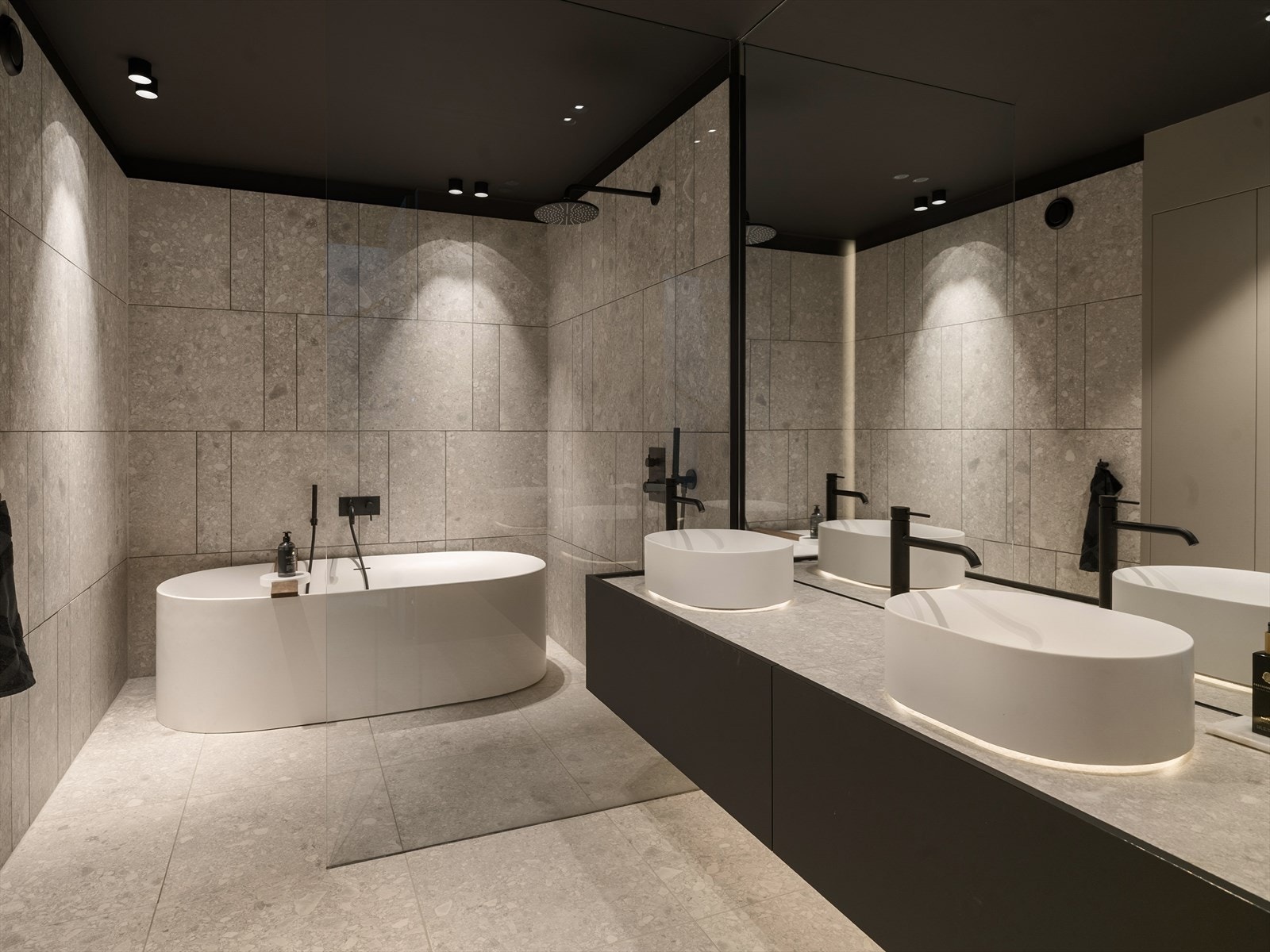 Dusj og badekar er elegant plassert bak en skjermvegg, mens fliser, spiler og integrerte armaturer gir rommet et helhetlig og stilrent uttrykk. Galleribilde