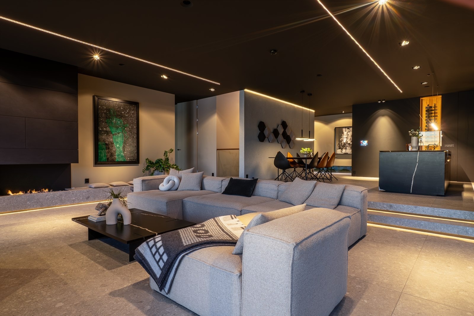 Steinplaten langs gulvet ved peisen fungerer både som visuell base og sitteplass, et gjennomtenkt grep som kombinerer komfort og design. Galleribilde