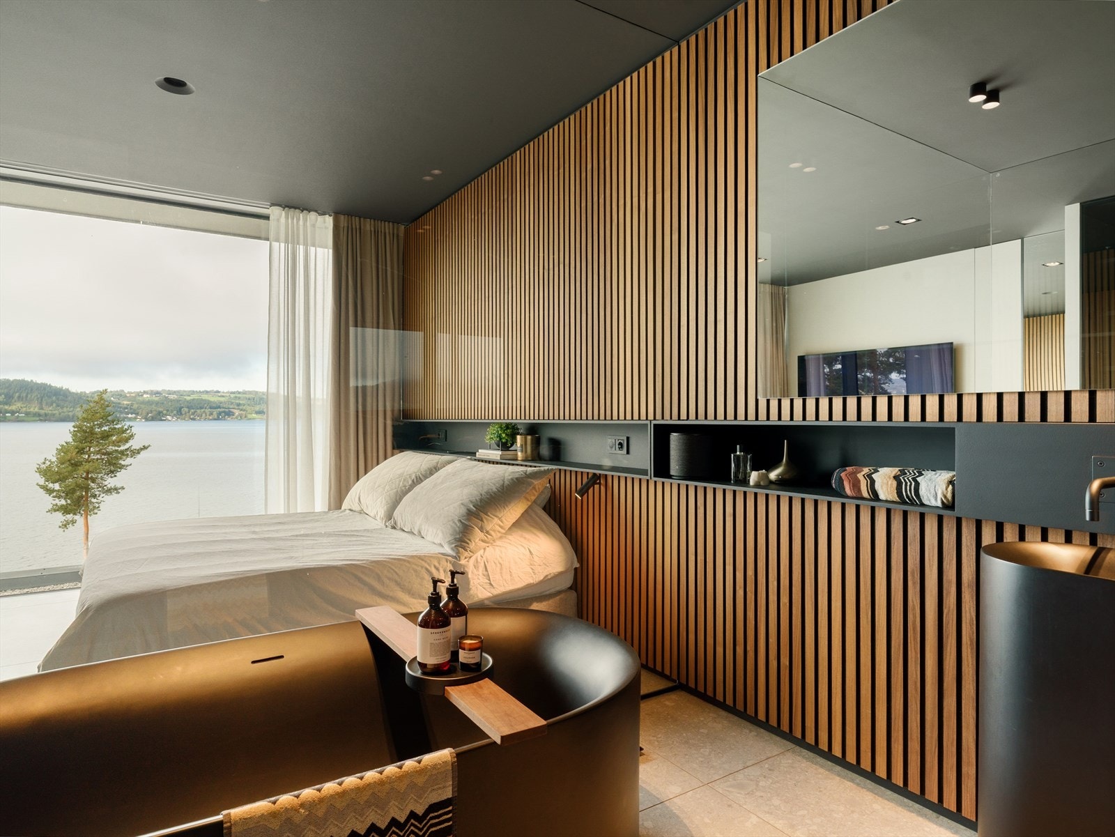 Valnøtt, glass og utsikt i samspill - Skjulte innredningsvegger med valnøtt spilefronter og plassbygde garderober gir en sømløs og eksklusiv helhet, der funksjon og form smelter sammen i et gjennomført interiørkonsept. Galleribilde