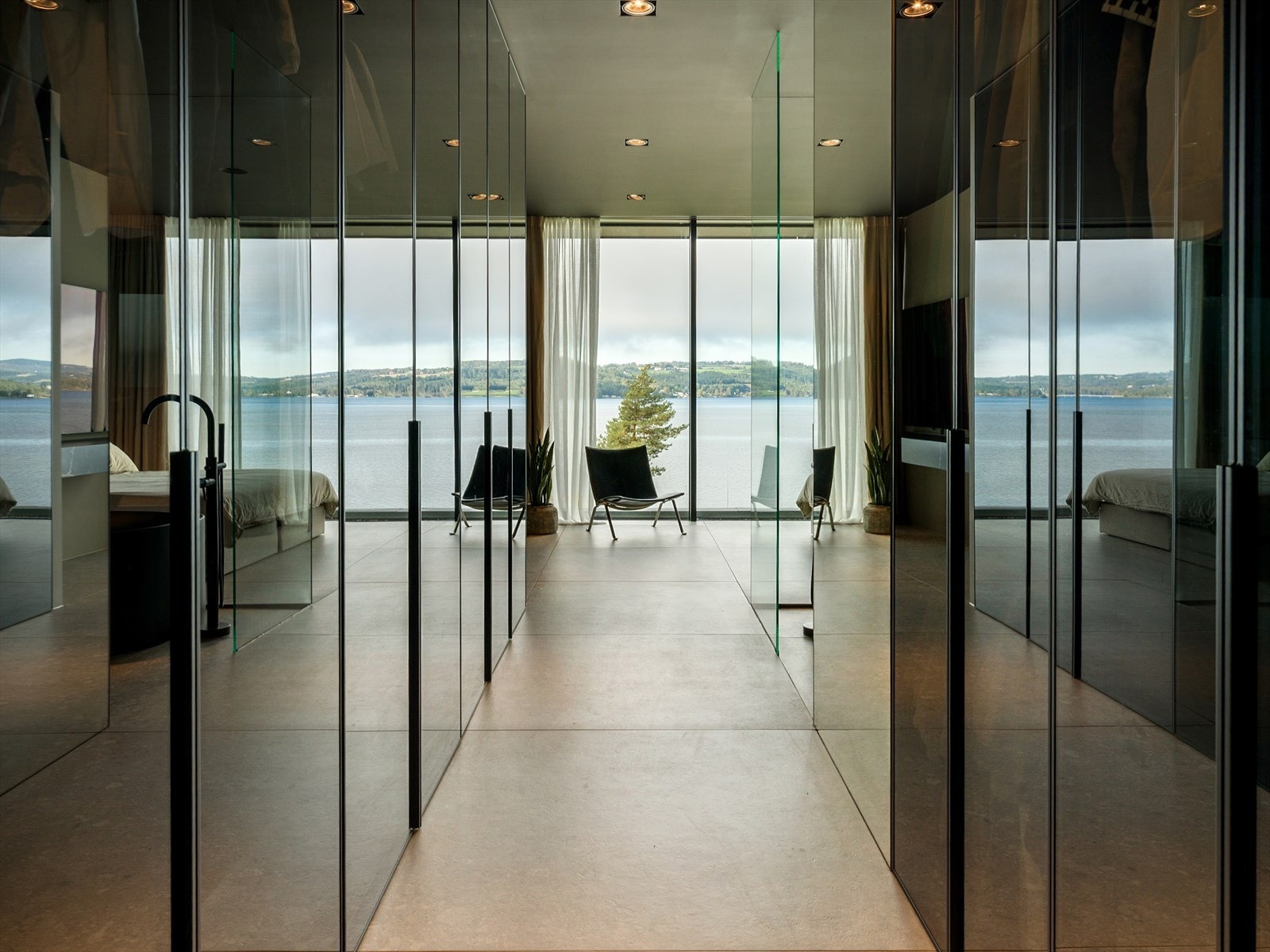 Skreddersydd luksus i hver detalj - Glassgarderobene i passasjen speiler både utsikt og dagslys, og skaper en luftig og elegant overgang mot hovedsoverom og bad med spesialbygde løsninger tilpasset boligens arkitektur. Galleribilde