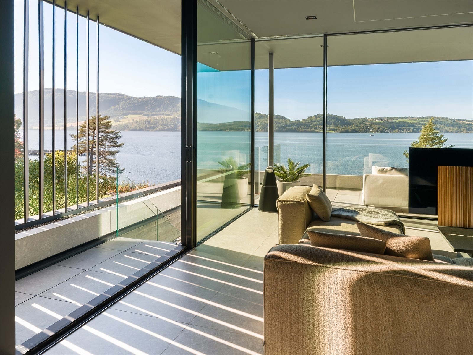 Infinity-følelse mot Mjøsa - De store vindusflatene gir en svevende romfølelse, der stuen nærmest flyter ut i landskapet med utsikt som tar pusten fra deg. Galleribilde