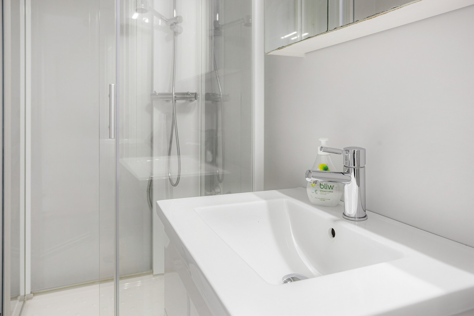 Den øvrige innredningen består av en servant med hvite skuffer og et tilhørende speilskap med belysning Galleribilde