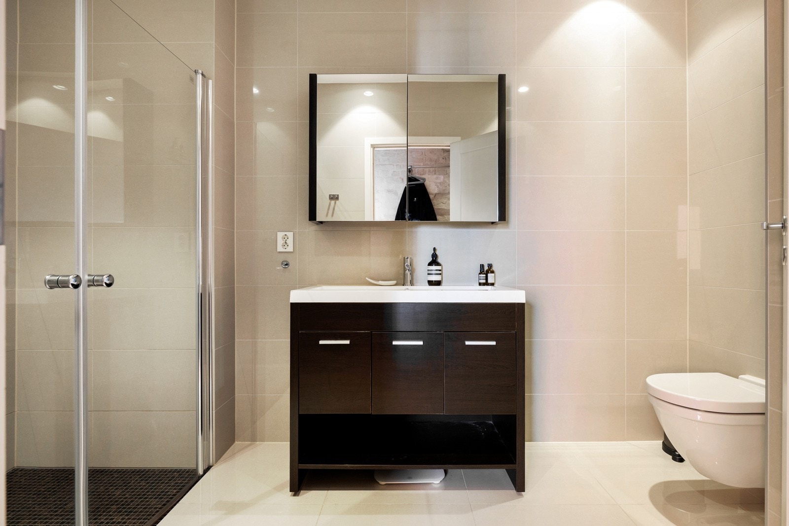 Badet fremstår moderne og delikat med store, lyse fliser på både gulv og vegger. Galleribilde