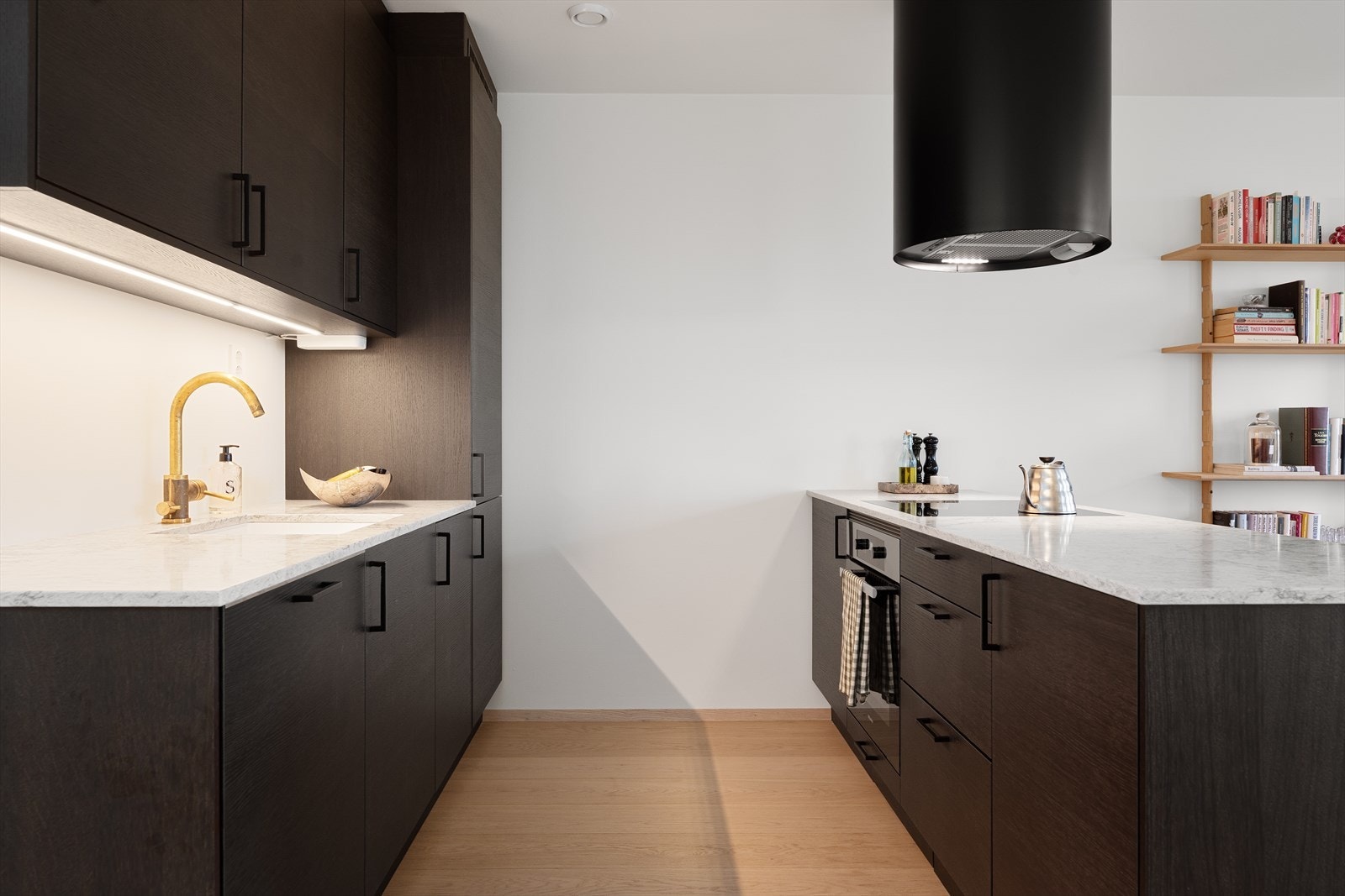 Innredningen består av både over- og underskap med god oppbevaringsplass, og det er montert belysning under overskapene. Mellom benkeplate og overskap er veggen malt i en lys tone. Galleribilde