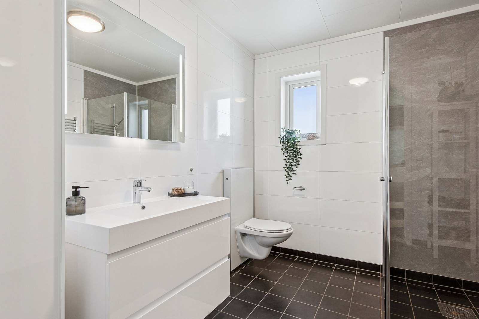 Baderomsinnredningen består av en heldekkende servant med skuffer og speil med integrert belysning. Galleribilde