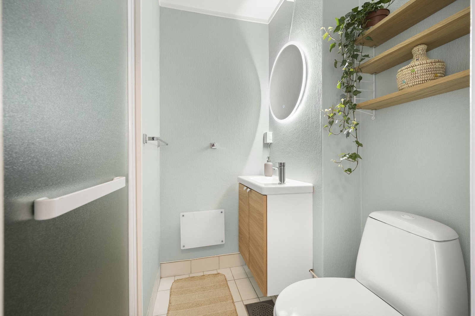 Badet har flislagt gulv og vegger med malt tapet. Badet er utvidet ut i stuen og ikke søkt godkjent dersom det ble etablert nytt sluk vedutvidelsen. Galleribilde