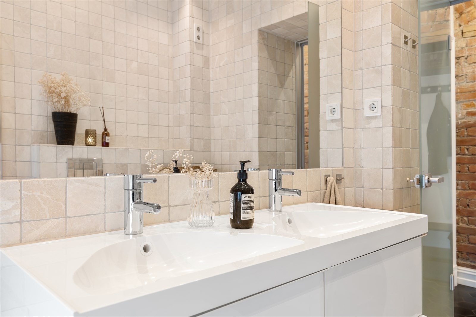 Dobbelservant med underskuffer og speilfelt i flis gir et elegant uttrykk. Badet har vegghengt toalett og opplegg for vaskemaskin og tørketrommel. Ny elektrisk vifte ble montert i 2020. Galleribilde