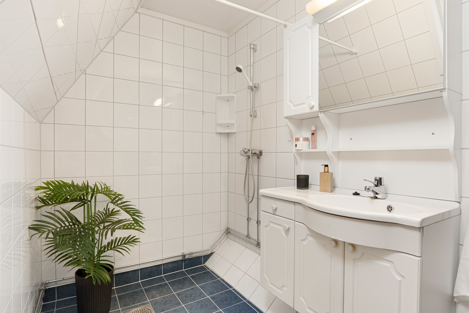 Romslig baderom fra ca. år 2000. Badet er utstyrt med vegghengt wc, servant i diverse innredning og dusj i hjørne. Galleribilde