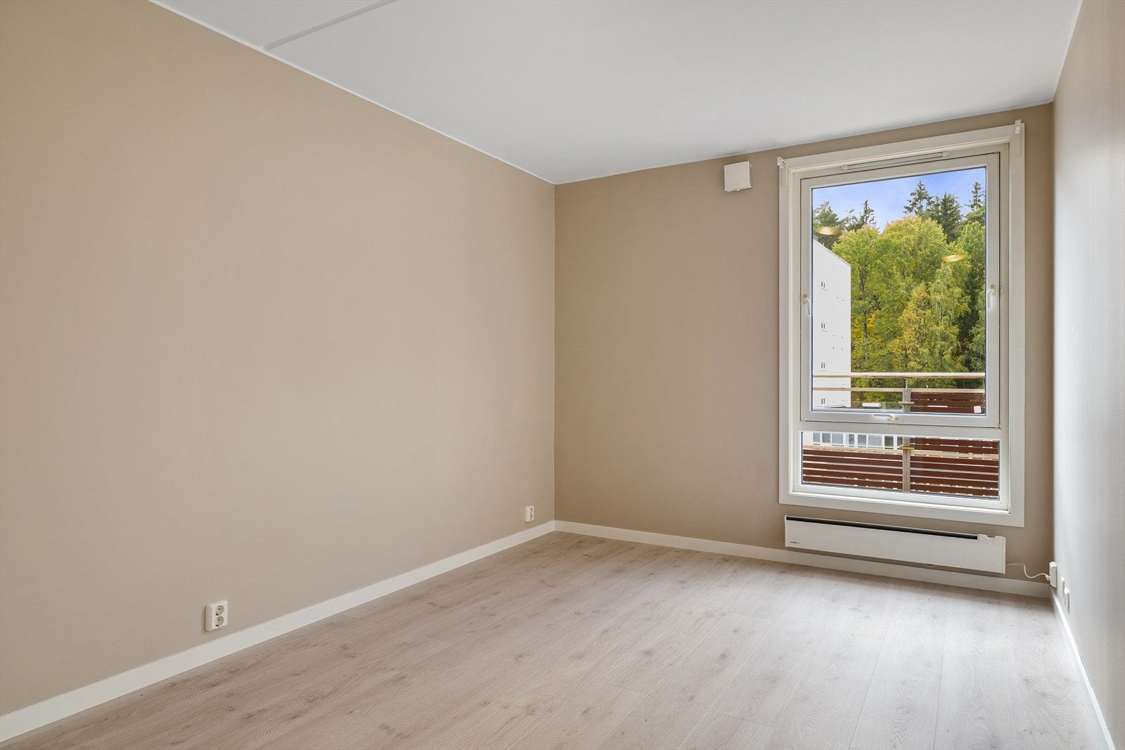 De lyse overflatene og det nylagte laminatgulvet gir et rent og moderne preg, mens vinduet vender mot rolige omgivelser og sørger for godt lysinnslipp. Galleribilde