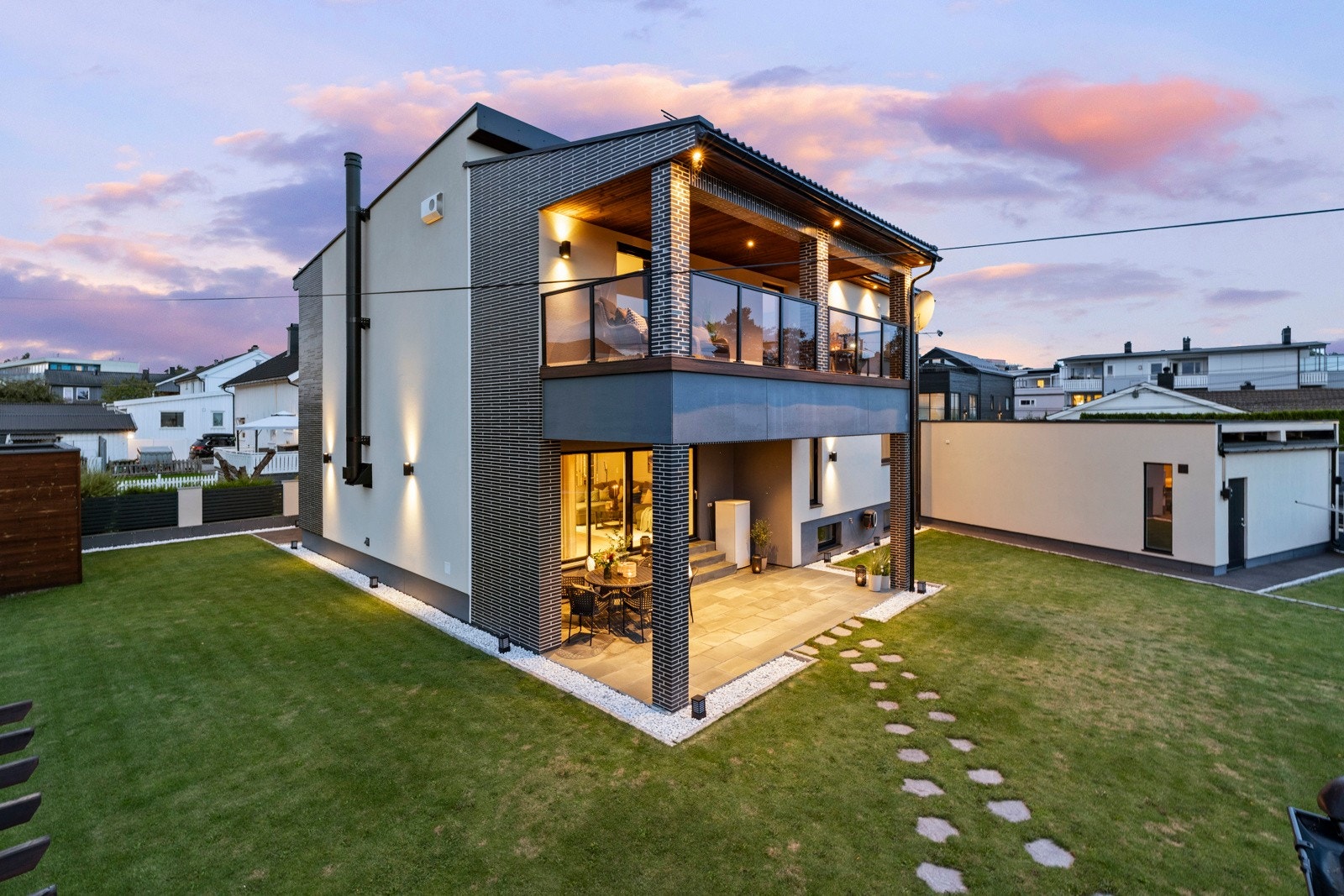 Tomt/fasade. Det er montert solcellepanel på både boligens og garasjens tak. Galleribilde