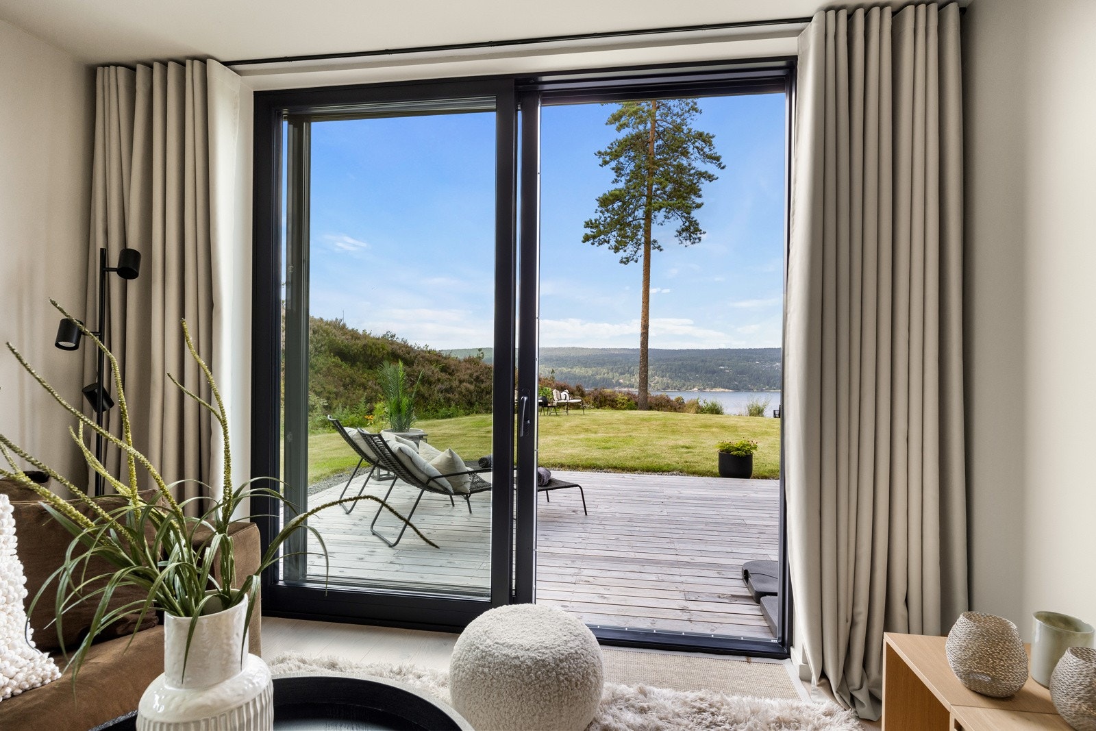 Fra tv-stuen er det utgang til terrasse og hage via store skyvedører i glass Galleribilde