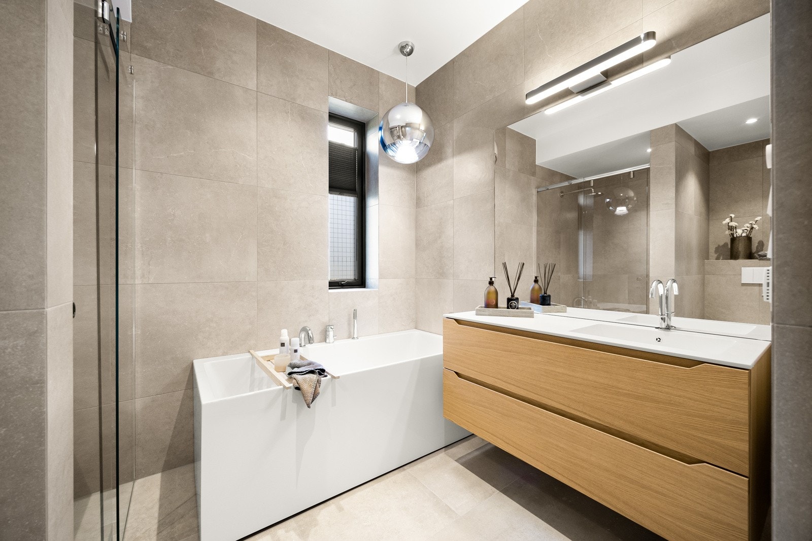 badene har store, delikate fliser på gulv og vegger, samt gulvvarme, downlights og veggmontert toalett Galleribilde