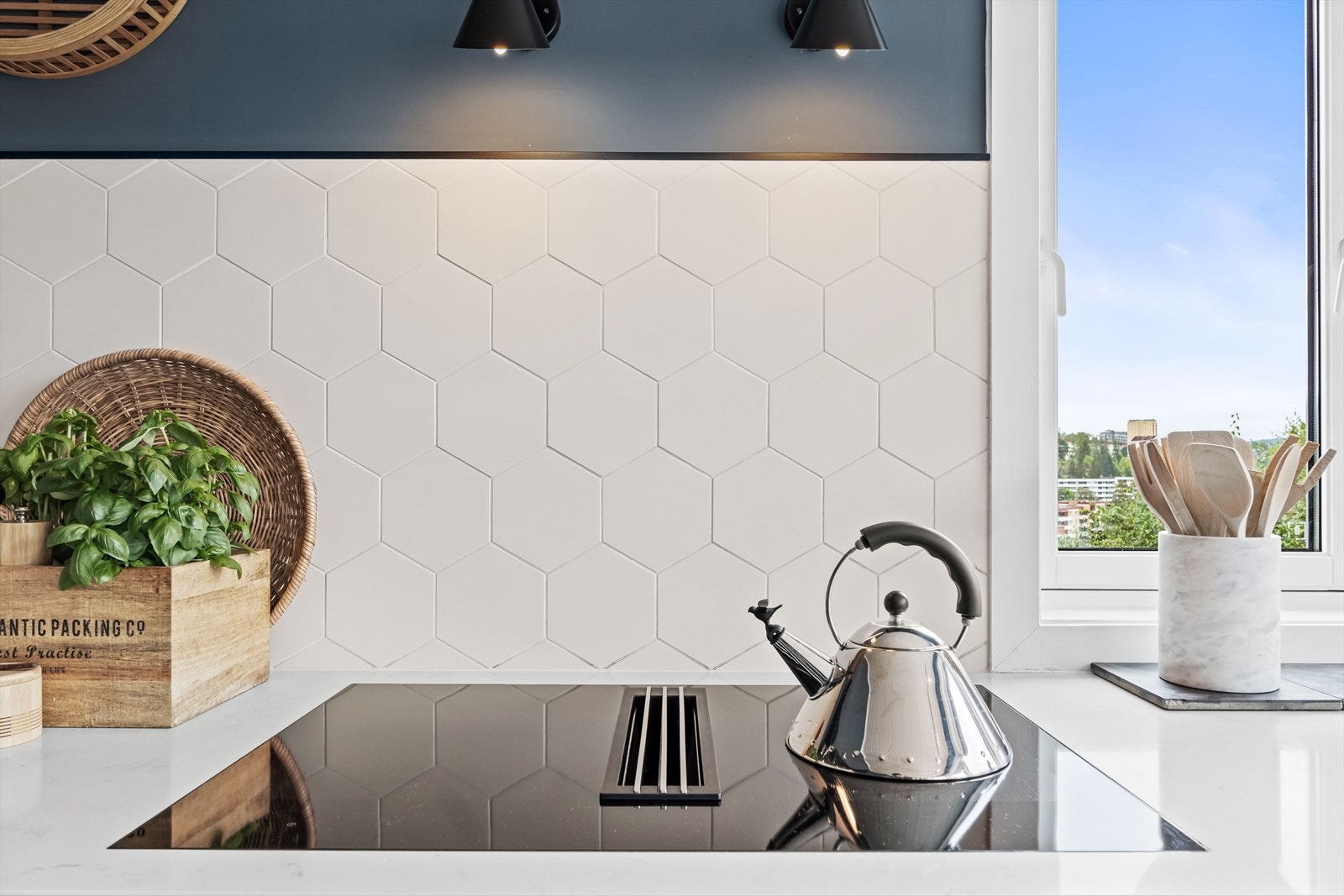 Stilige detaljer med hexagon-fliser som sprutplate, AJ vegglamper fra Louis Poulsen og flott utsikt fra kjøkkenet. Galleribilde