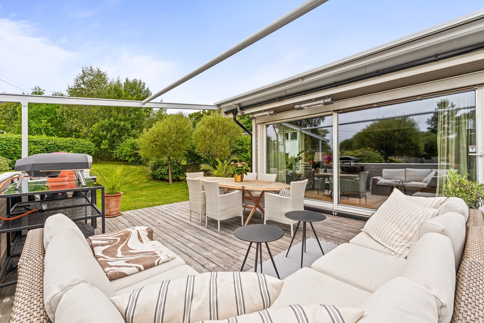 Terrassen har god plass til sofa, spisebord og grill. Varmelamper med integrerte høyttalere montert over spisebordet. Galleribilde