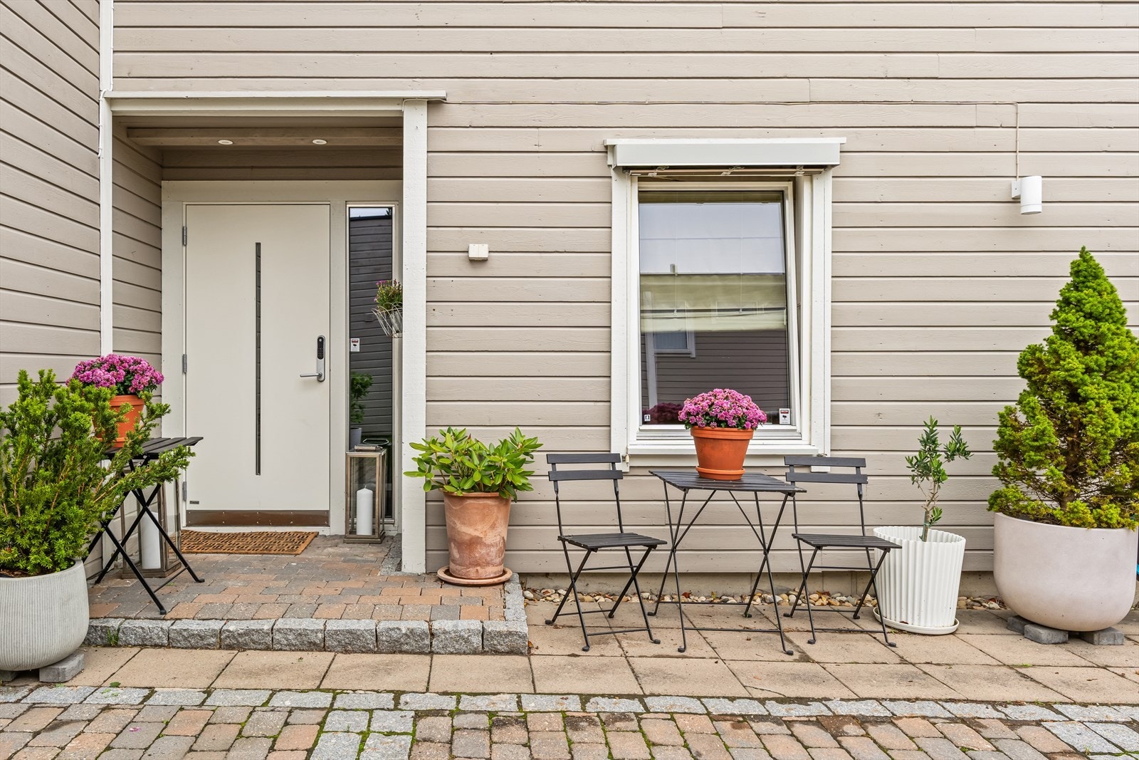 Overbygget inngangsparti med downlights. Pent opparbeidet gårdsplass med brostein, elvestein og moderne utebelysning. Galleribilde