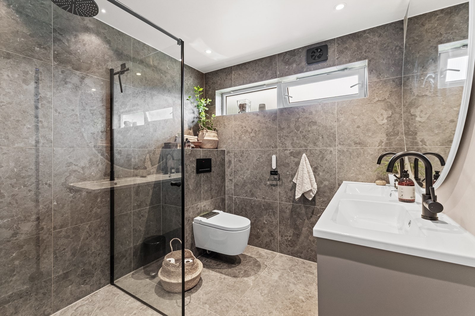 Delikat flislagt baderom totalrenovert i 2021 med gulvvarme, 60x60 fliser, stilren INR baderomsinnredning med dobbel servant og store skuffer. Innebygget sisterne og vegghengt Geberit toalett med spylefunksjon. Elektrisk avtrekksvifte i yttervegg. Galleribilde