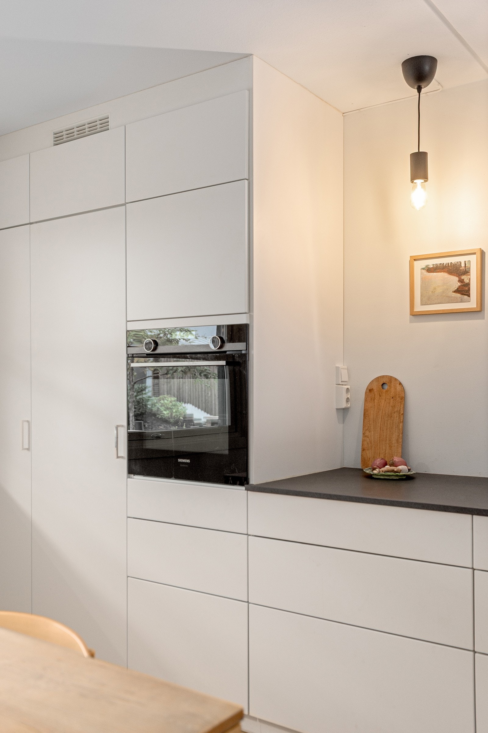 Smart oppbevaring i høyskap gir et åpent og luftig kjøkken med god arbeidsflate over kjøkkenbenken. Galleribilde