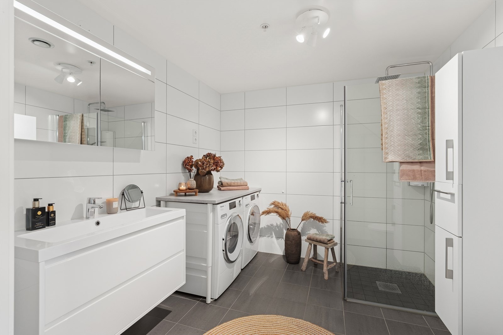 Rommet er innredet med nedfelt servant, veggmontert toalett og dusjhjørne med dusjvegger, samt opplegg for vaskemaskin og tørketrommel. Galleribilde