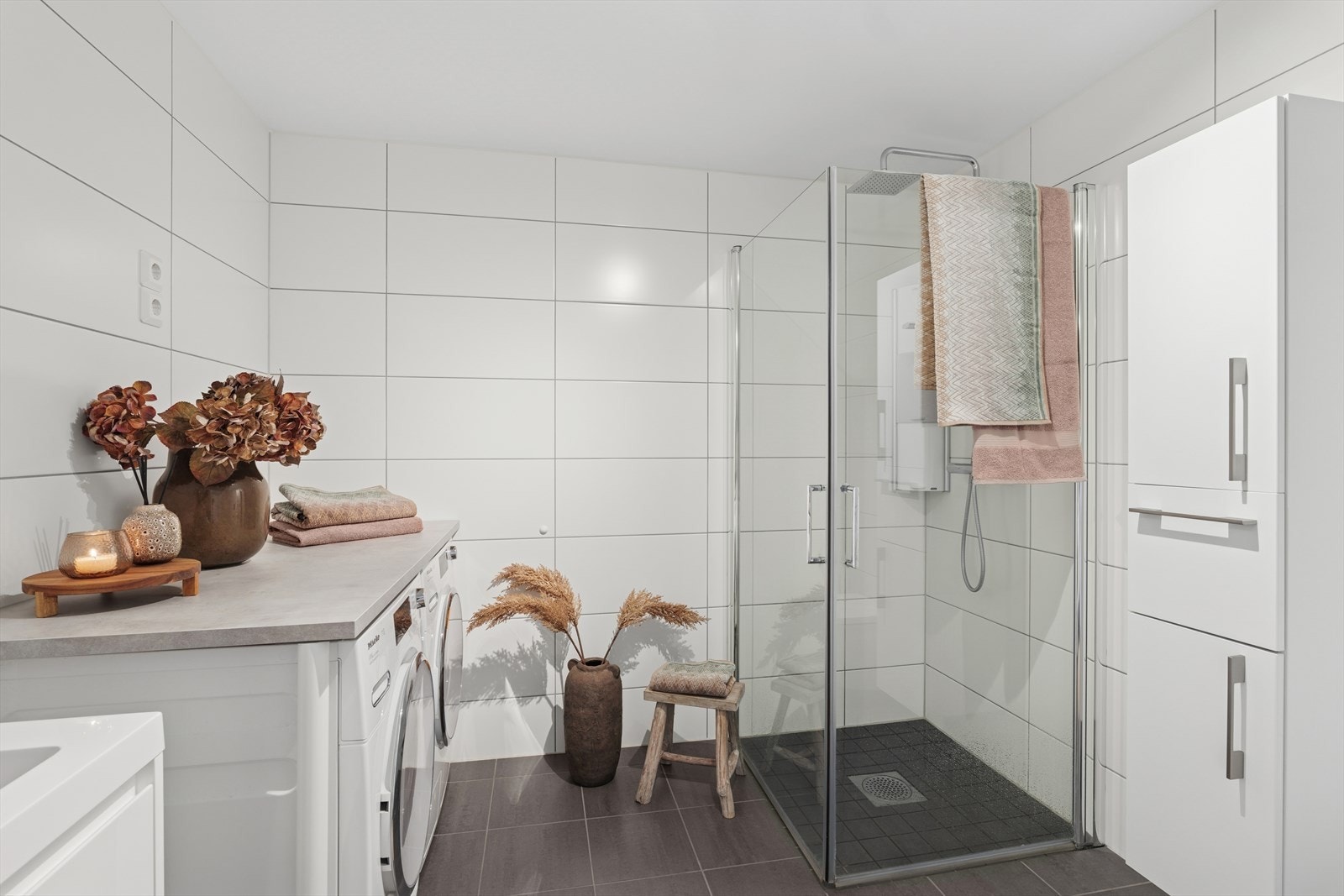 Badet fremstår moderne og funksjonelt med flislagt gulv og varmekabler, flislagte vegger og malt, slett tak. Galleribilde