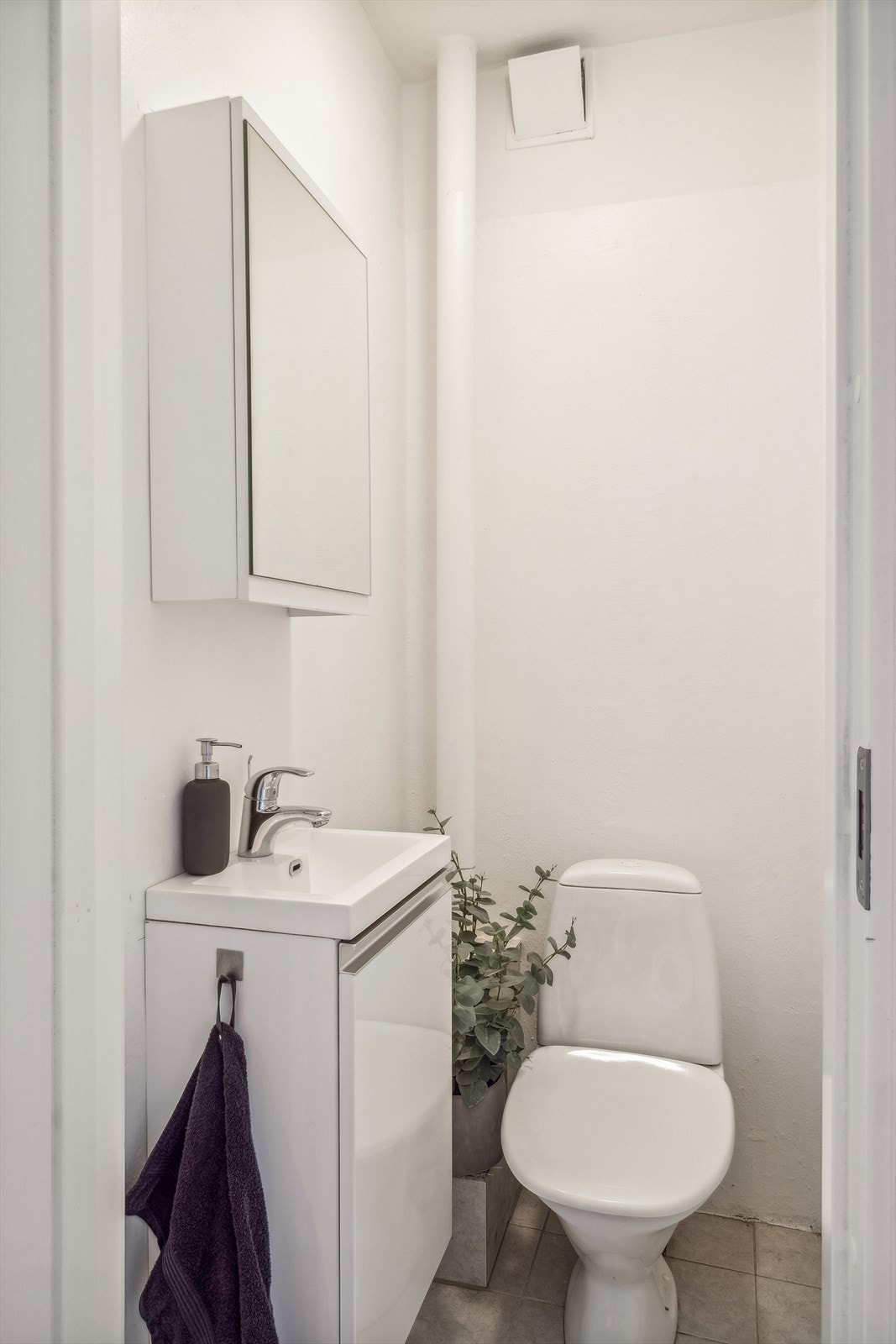 Toalettrommet har lysmalte plater på veggene og lysgrå fliser på gulvet. Rommet er innredet med heldekkende servant montert på skapinnredning, speilskap og gulvmontert toalett. Det er naturlig avtrekk etablert. Galleribilde