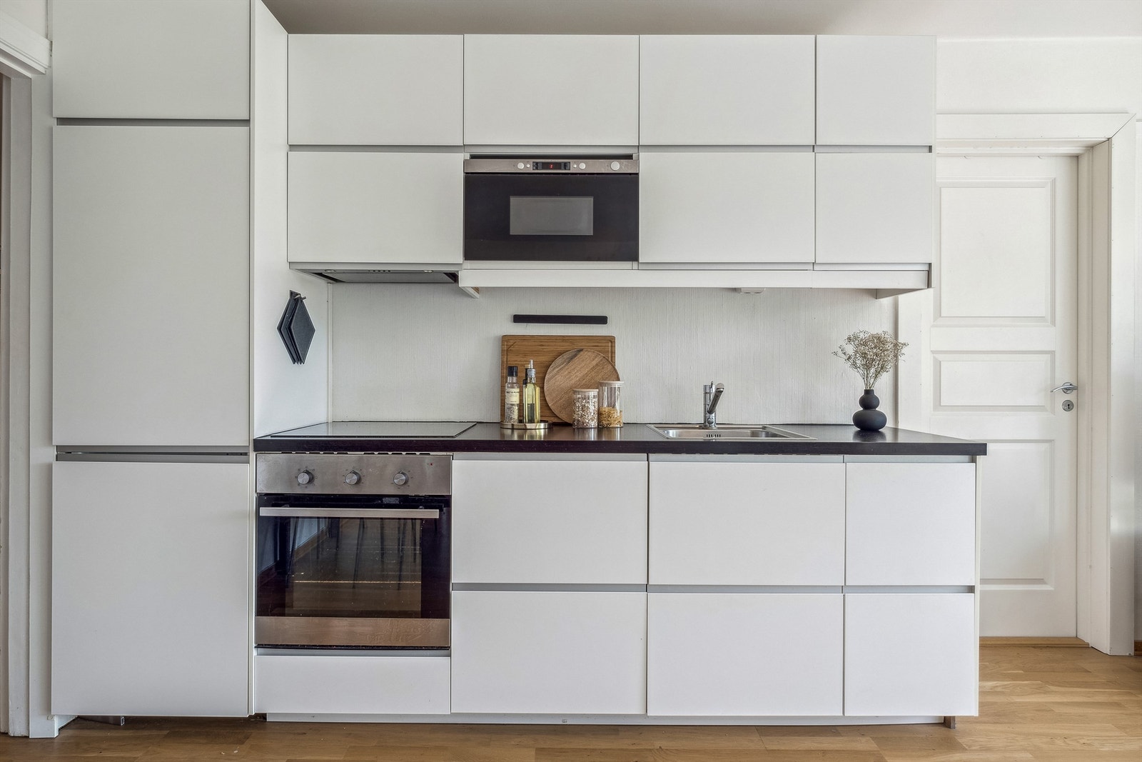 Kjøkkeninnredning med lyse, laminerte skrog og benkeplater. Glattefronter på over- og underskap og skuffer. Galleribilde