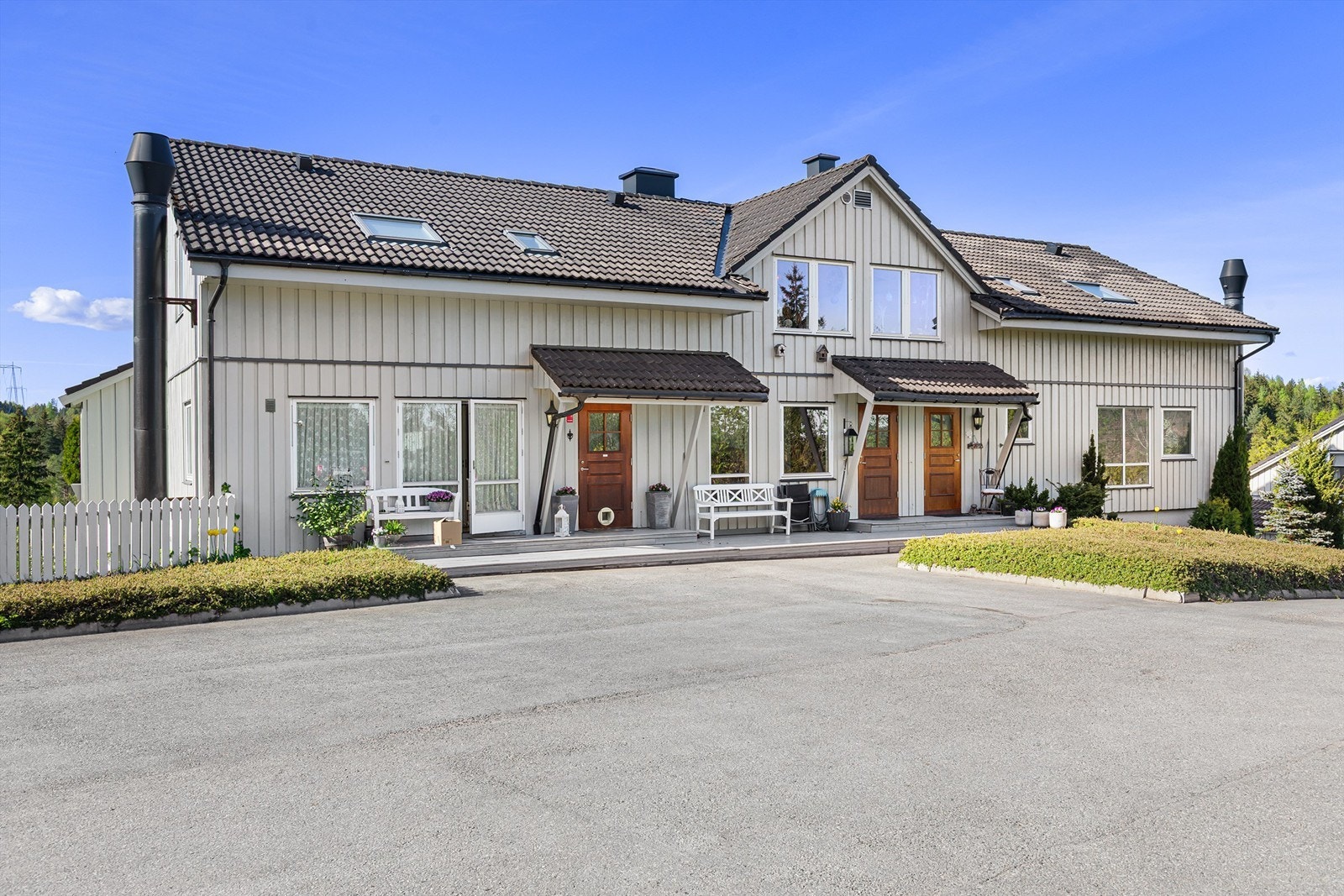 Asfalterte parkeringsplasser utenfor inngangspartiet ovenfor blokka, samt liten platting man kan nyte morgensol Galleribilde