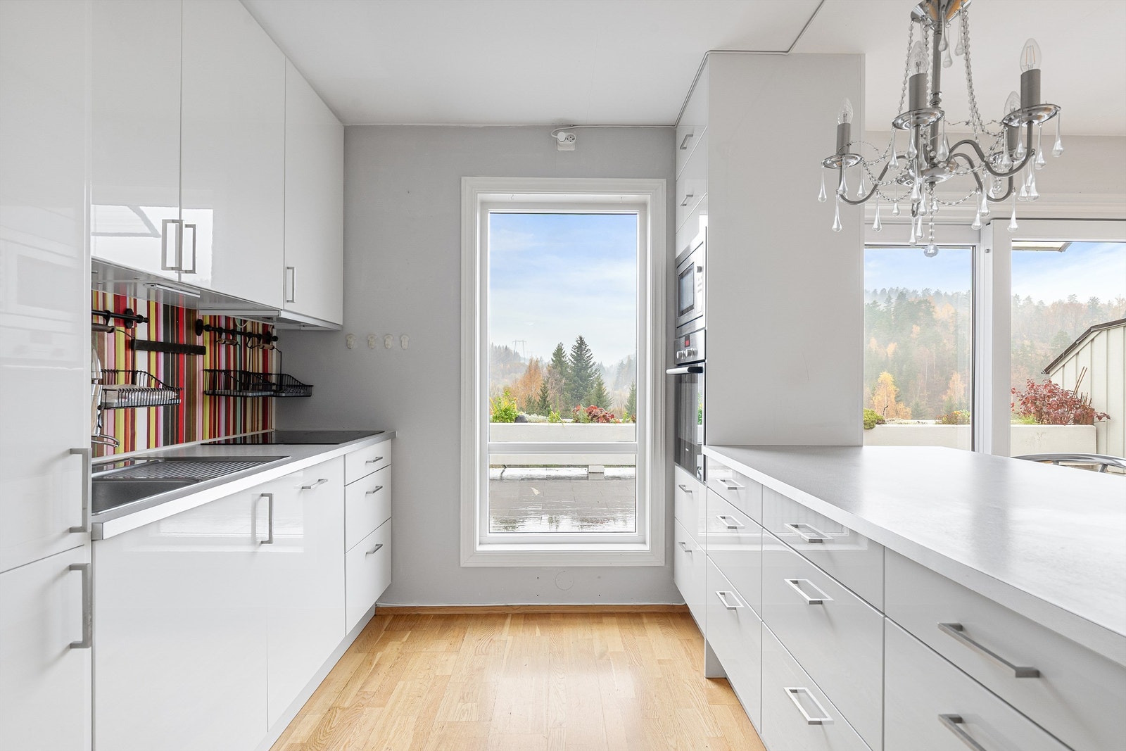 Kjøkkenet er innredet med over- og underskap i lyse slette fronter og har rikelig med både skap- og benkeplass Galleribilde