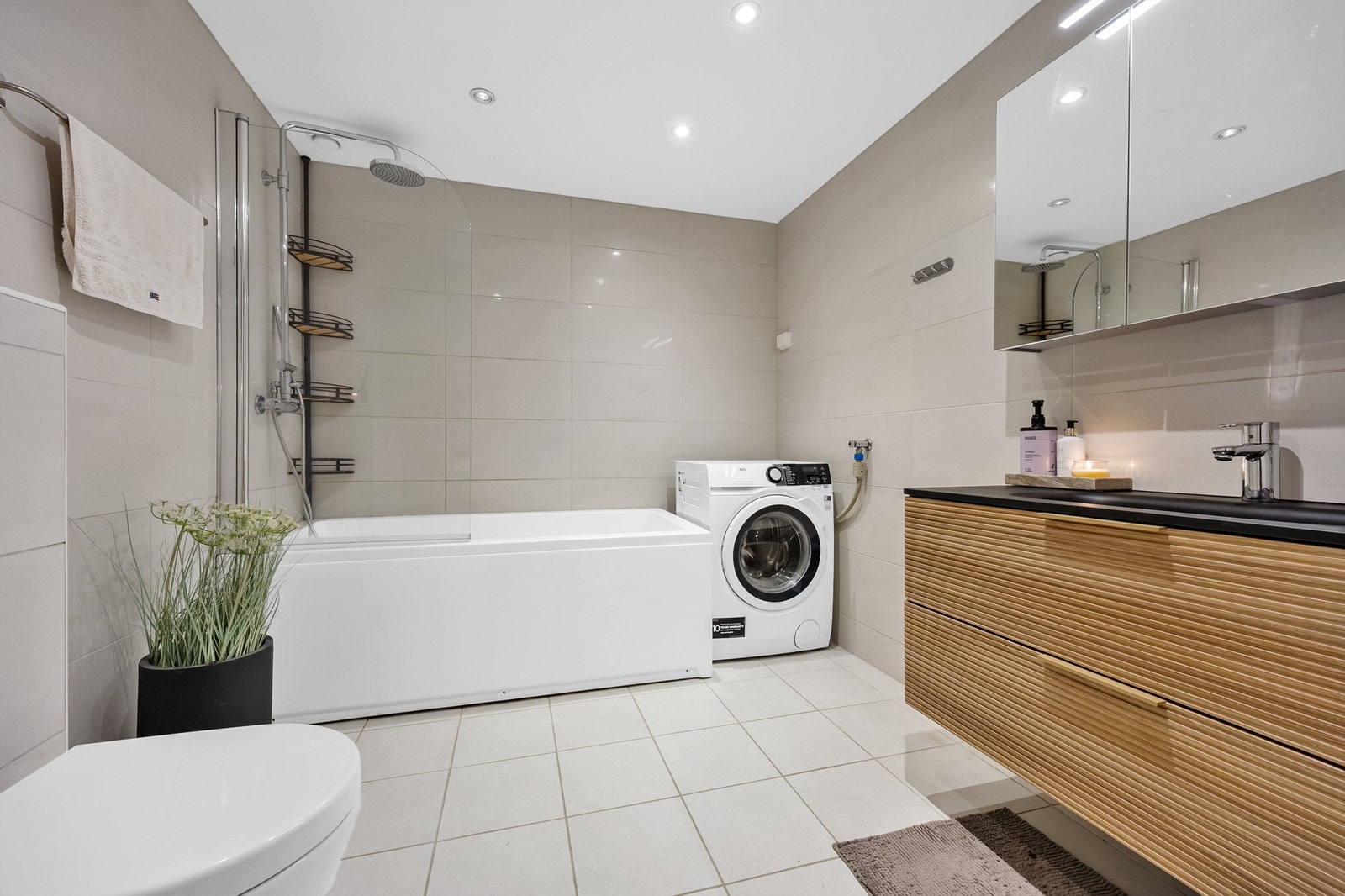 Stilig flislagt bad med beige gulv- og veggfliser og downlights i himling. Galleribilde