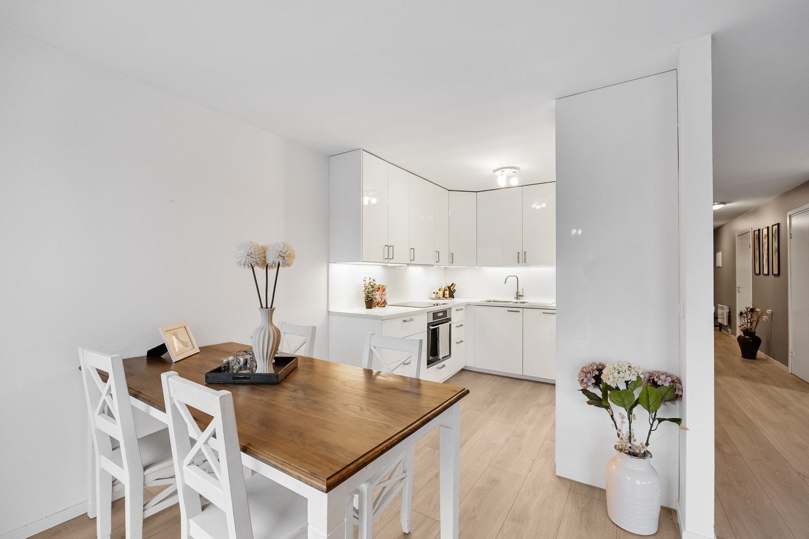 Stilrent kjøkken i L-form med integrerte hvitevarer. Galleribilde