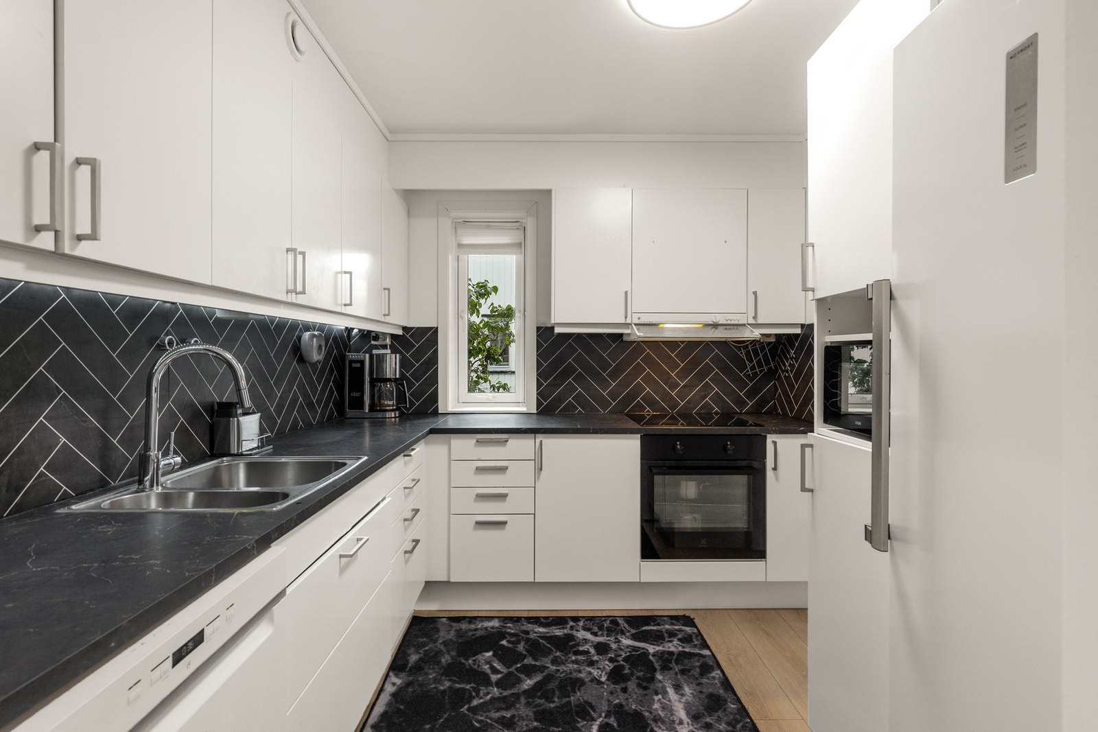 Stilren kjøkkeninnredning hvor dagens eier har oppgradert kjøkkenet i 2023 med nye skapdører, komfyr, platetopp, vask, blandebatteri, samt nye og slitesterke plater på vegg over benkeplate. Galleribilde