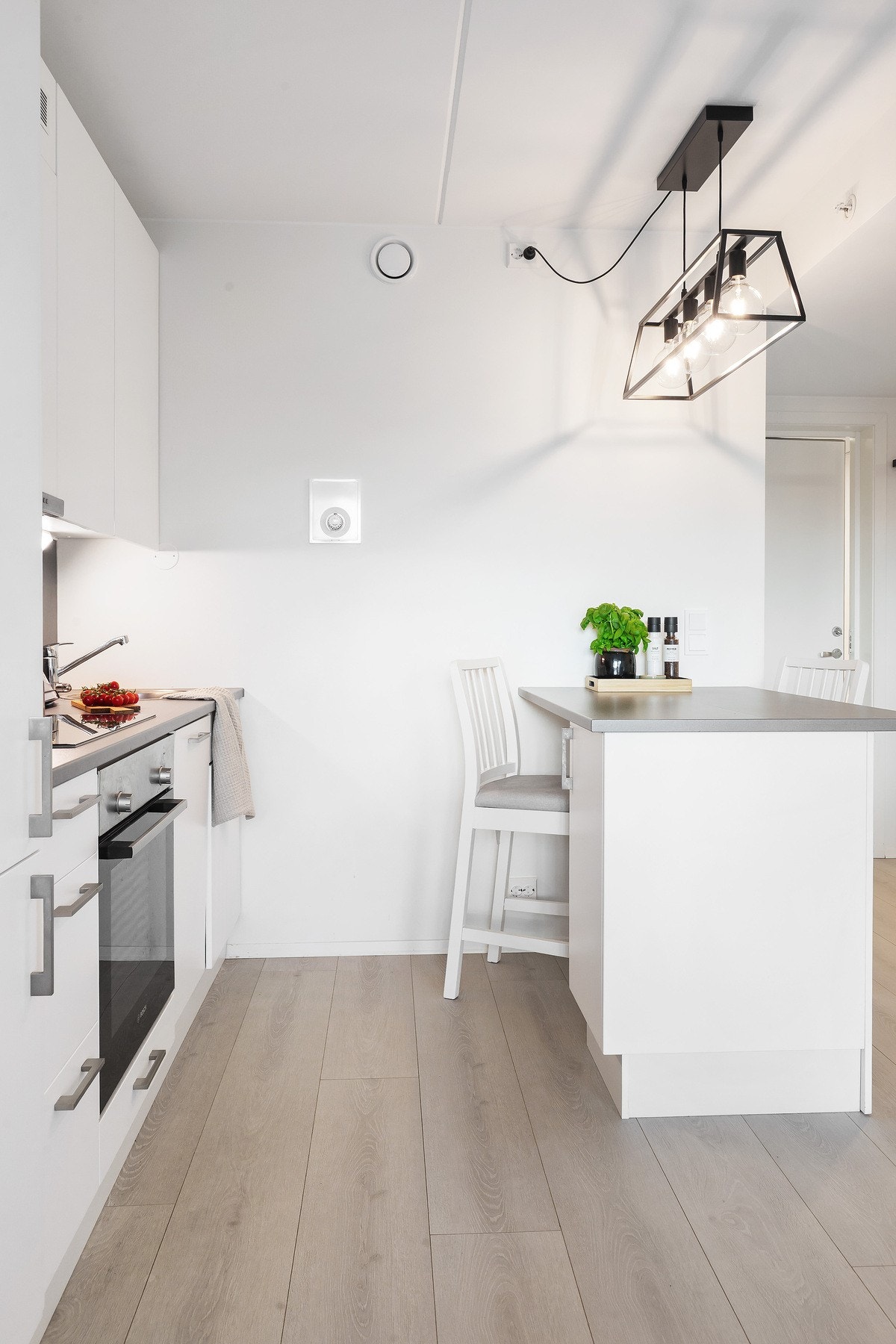 Kjøkkenøyen gir ekstra bruksområder som ytterligere benkeplass, oppbevaring i skap og et spisebord med plass for to Galleribilde