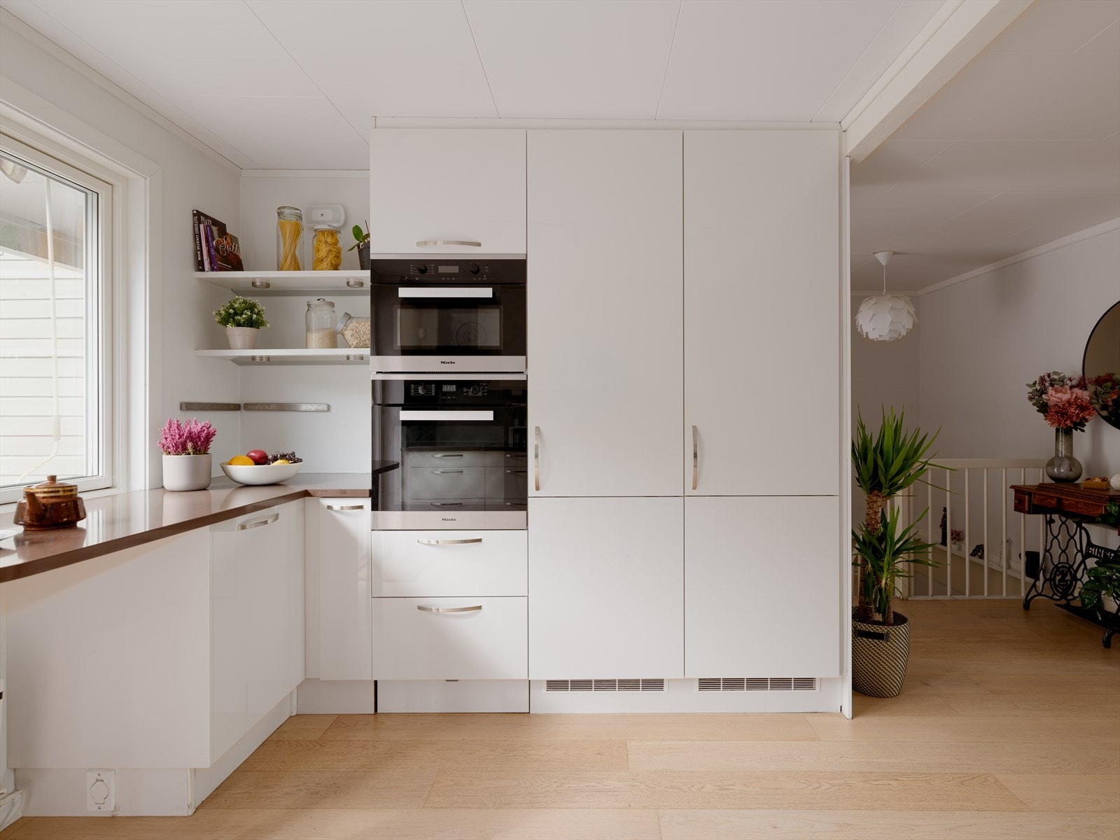 Komfyr med induksjons platetopp, mikrobølgeovn, oppvaskmaskin samt kjøleskap og fryseskap som høyskap er integrert i innredningen. Galleribilde