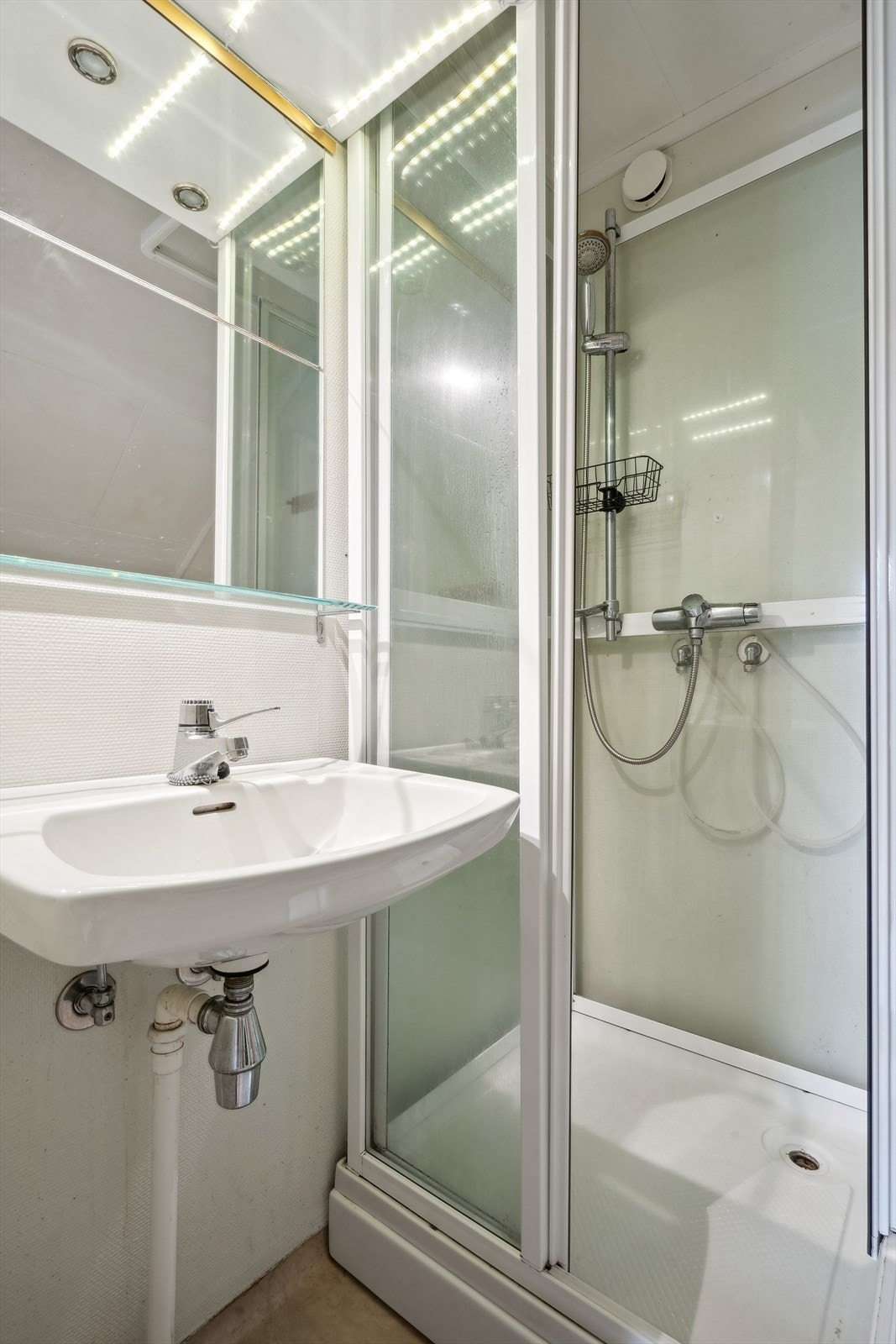 Baderommet har vinylbelegg med oppbrett på gulv og malt strie på veggene, samt takess i himling. Galleribilde