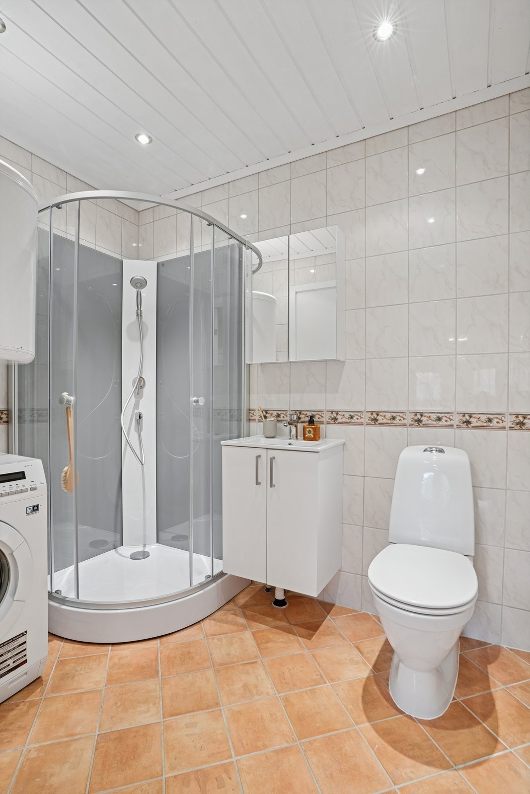 Badet i gjestefløyen som er innredet med dusjkabinett, wc og opplegg for vaskemaskin. Galleribilde