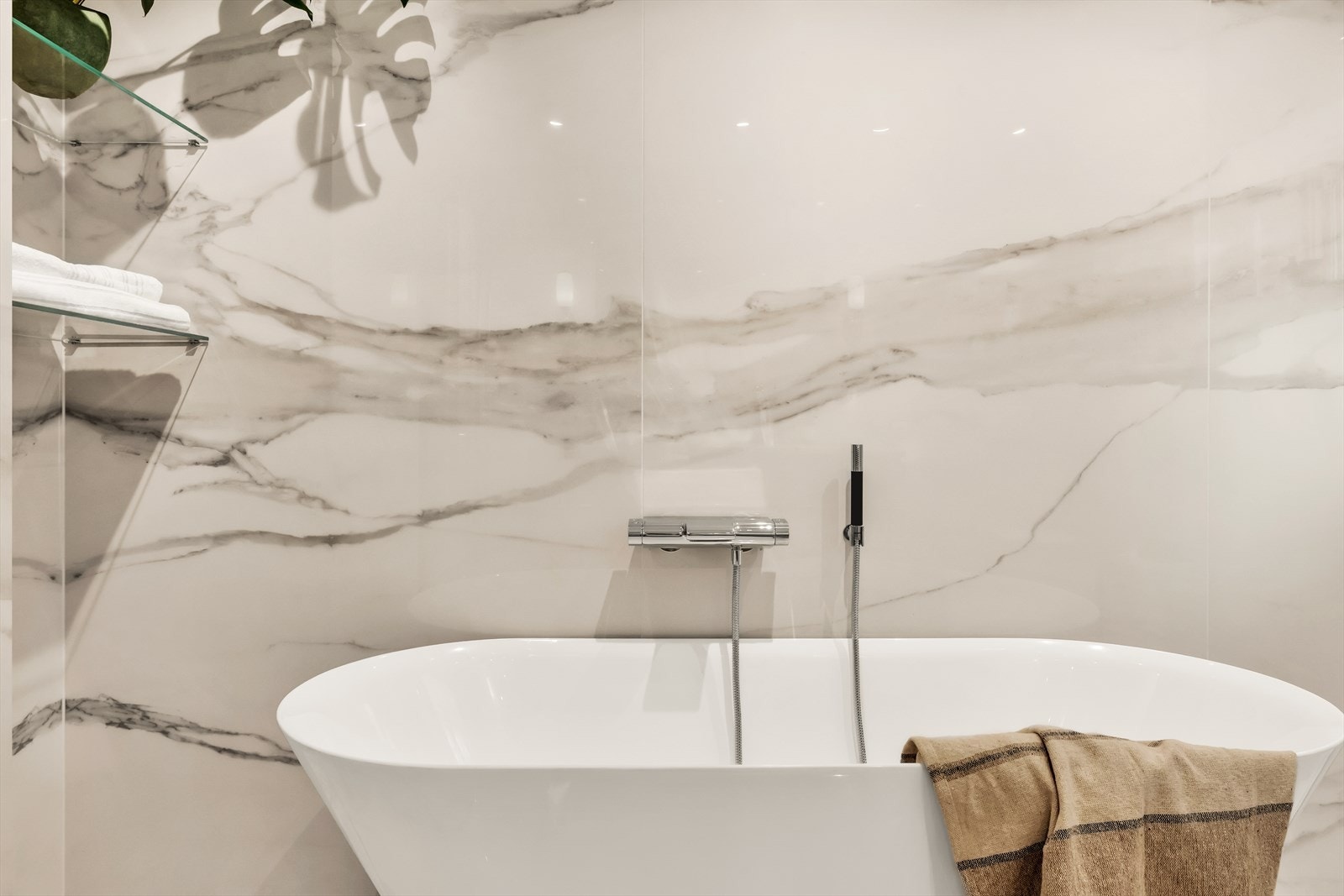 Videre er badet utstyrt med speil, vegghengt wc, badekar og dusjnisje med regn- og hånddusj fra Grohe Galleribilde