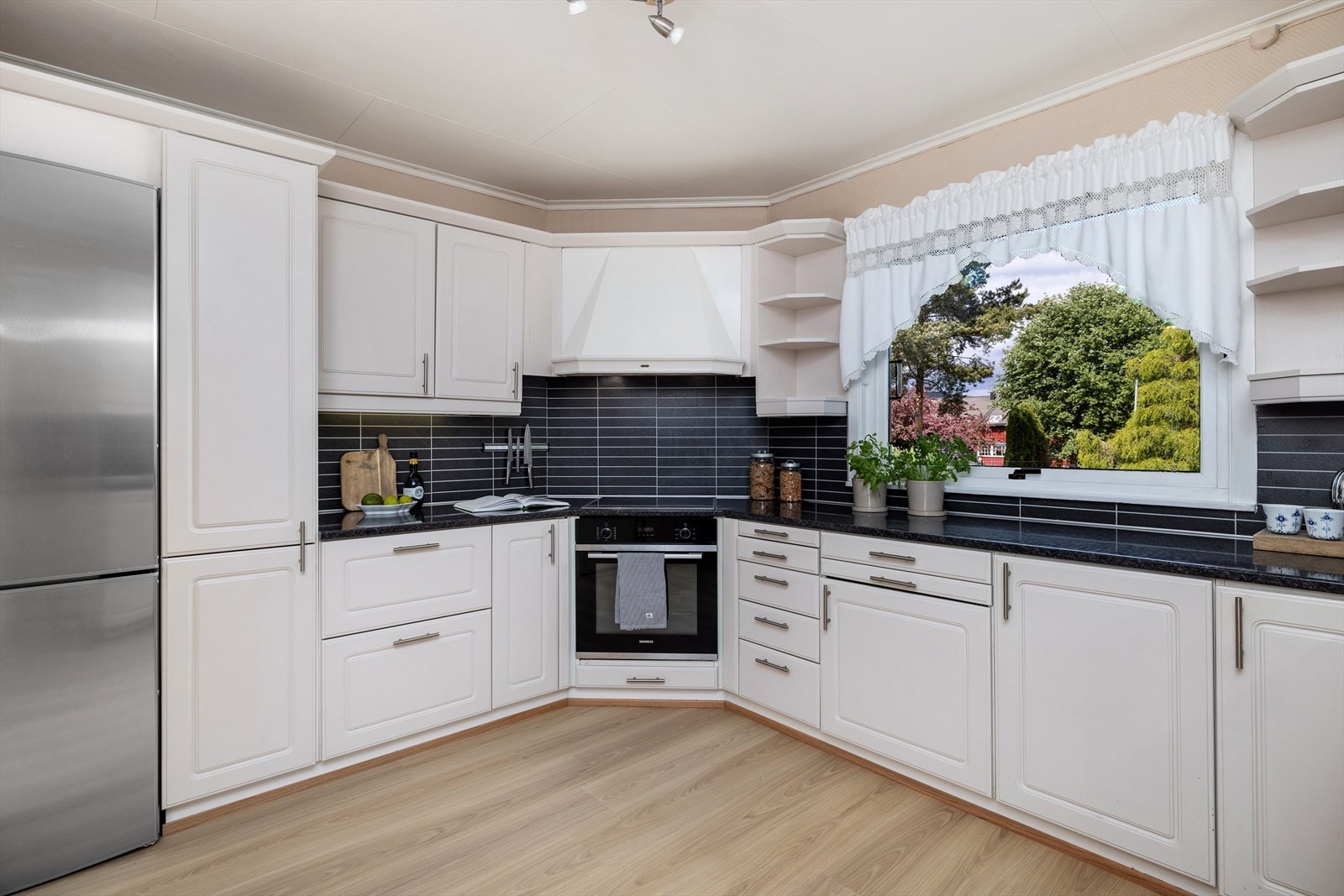 Lyst og pent kjøkken med stort vindu ut mot gårdsplass. Galleribilde