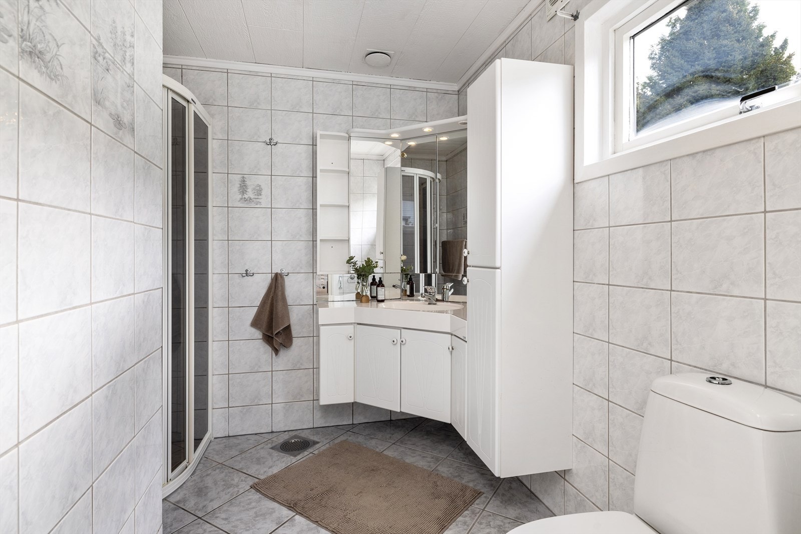 Bad i hovedetasjen er av eldre dato med flislagte gulv og vegger. Dusjnisje. Varmekabler i gulv. Galleribilde