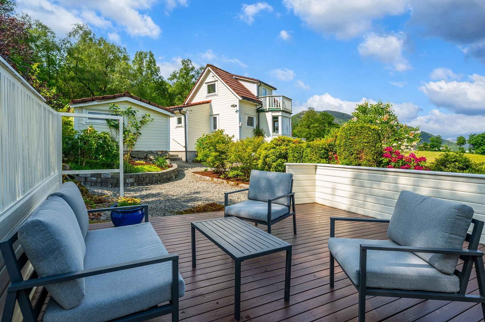 Det flotte uteområdet med terrasser, bed, busker og plen skaper en idyllisk ramme. Galleribilde