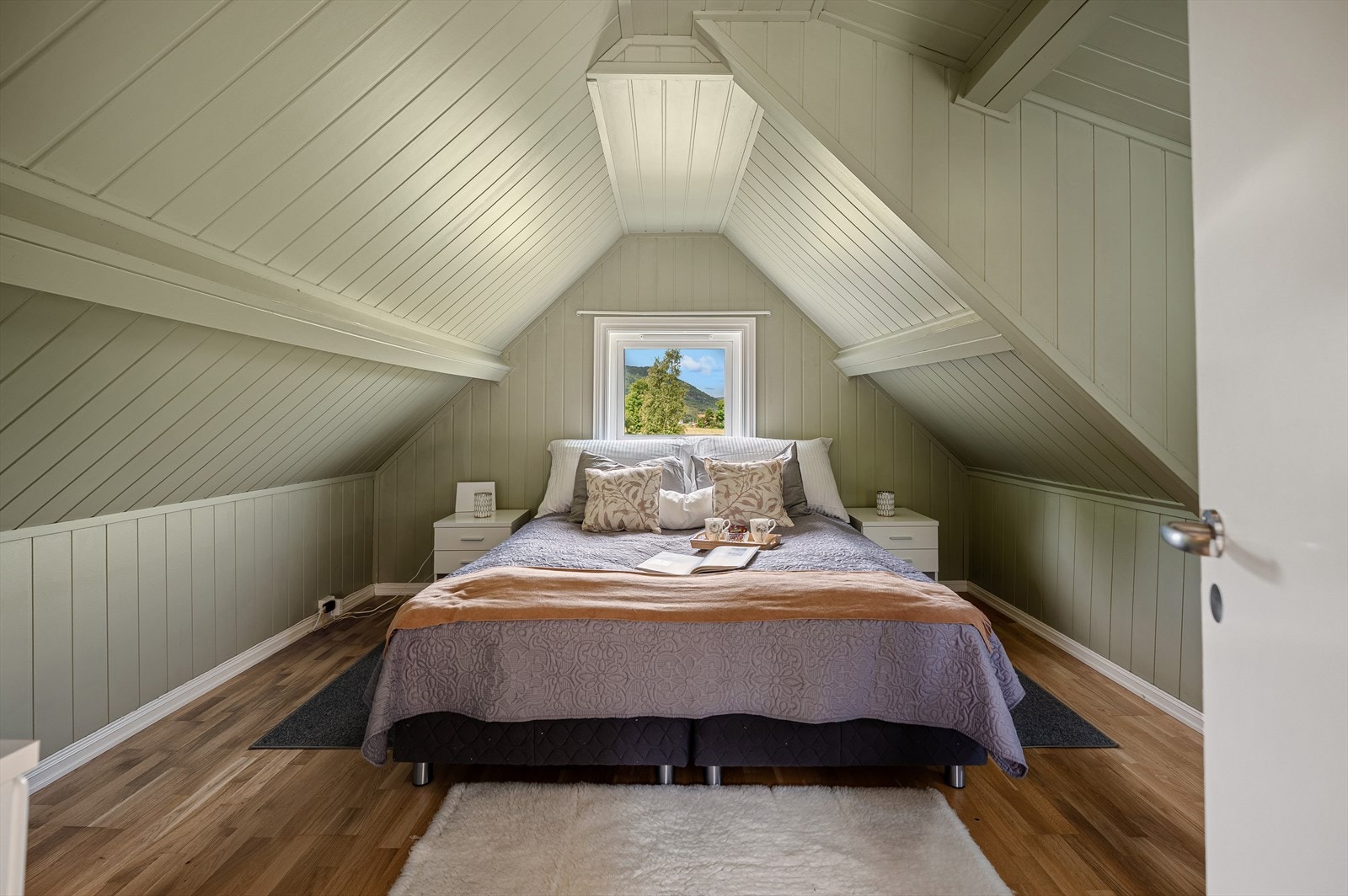 Soverommet utstråler en rolig eleganse med sin naturlige duse grønnfarge på både vegger og tak. Dette fargevalget skaper en innbydende og litt majestetisk atmosfære, perfekt for hvile og refleksjon, og gir rommet en følelse av dybde og harmoni. Galleribilde