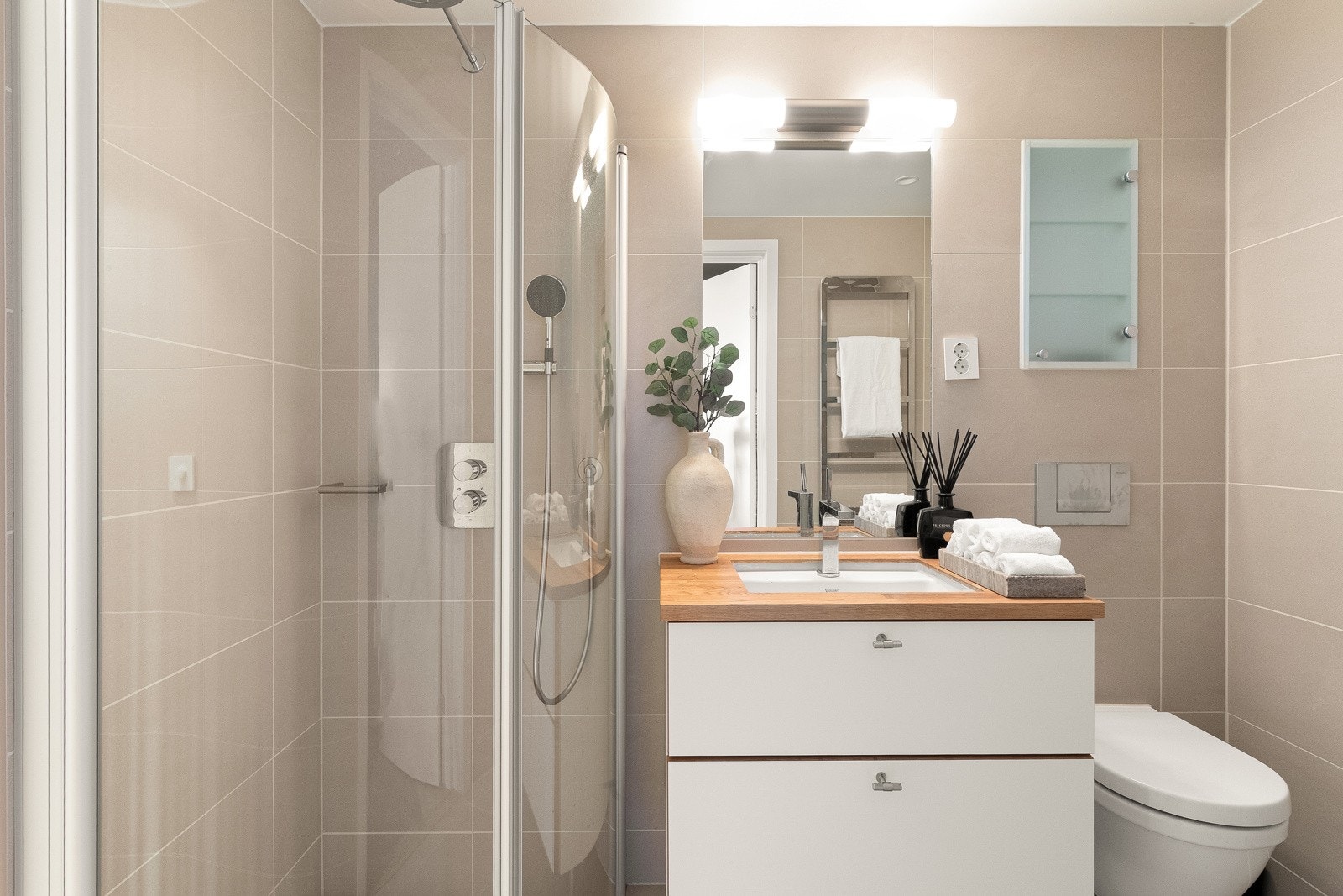 Badet har vegghengt toalett og dusj med innfellbare glassvegger og regnfallsdusj Galleribilde