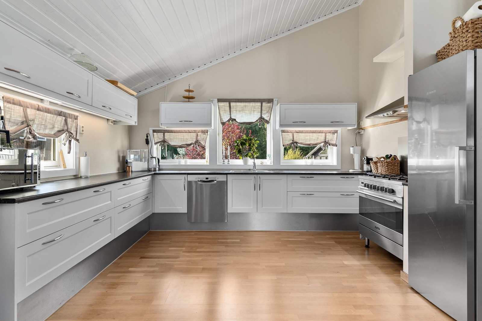 Romslig og lyst kjøkken med over- og underskap i profilerte fronter. Åpen planløsning mot stue og spisestue Galleribilde