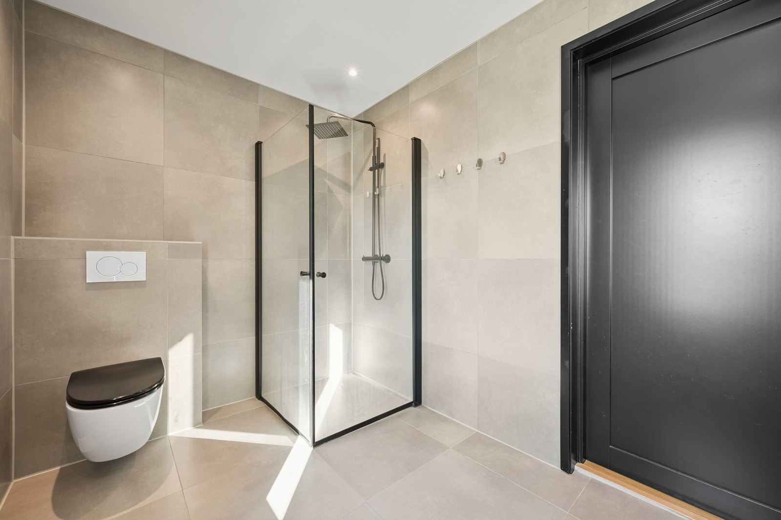 Badet har vegghengt toalett og dusjhjørne med innfeldbare vegger Galleribilde