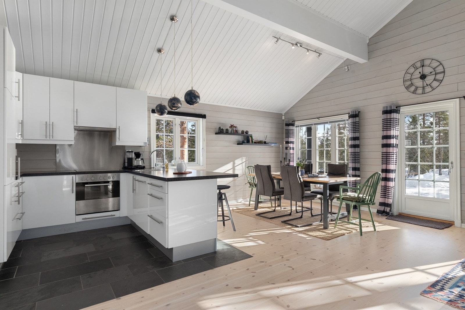 Kjøkkenet innredet med over- og underskap i lyse slette fronter med integrerte hvitevarer som kjøl/frys, platetopp, stekeovn og oppvaskmaskin Galleribilde