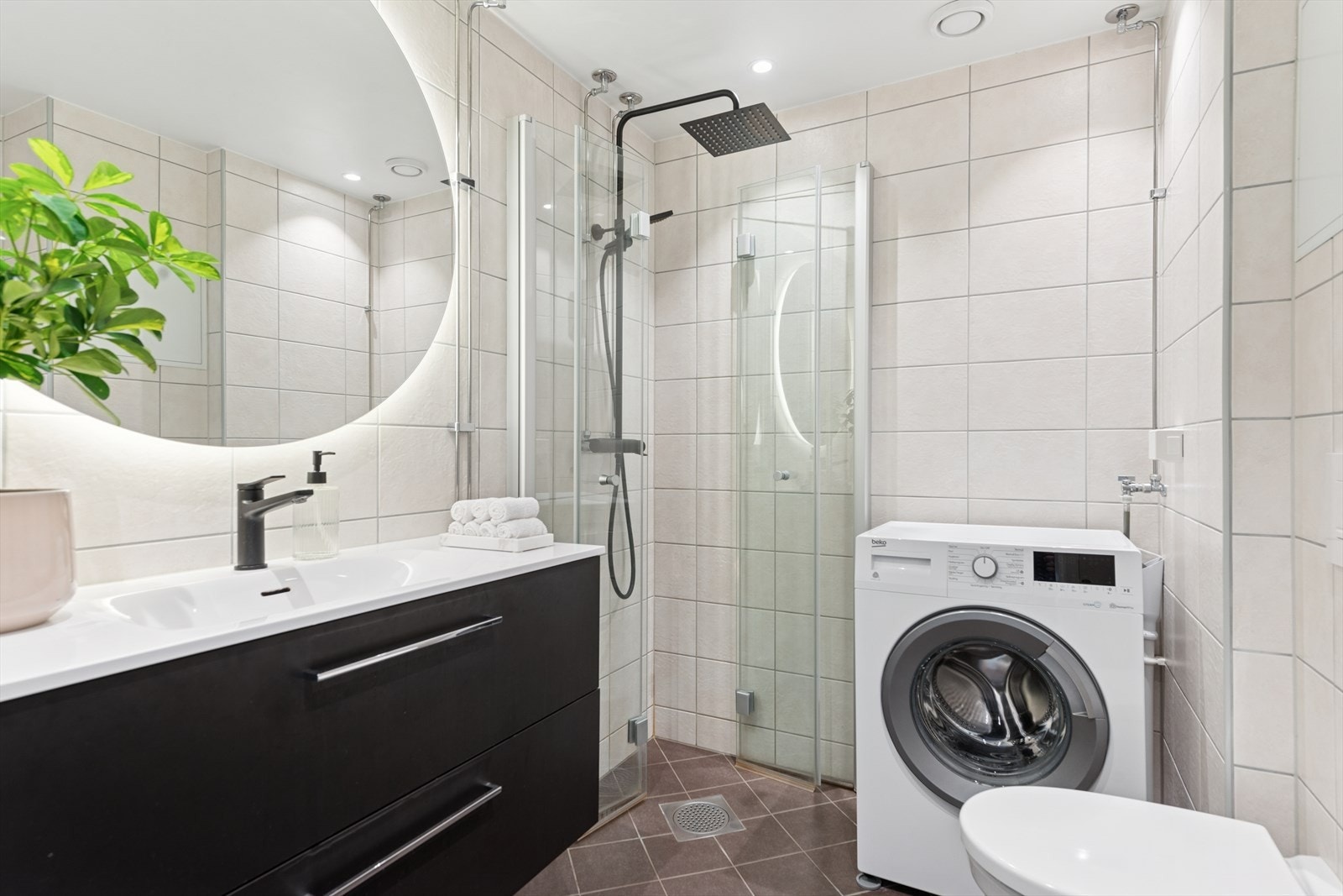 Nytt, flislagt bad med servant, veggmontert dusj, dusjvegger av glass samt veggmontert wc. Opplegg for vaskemaskin. Galleribilde