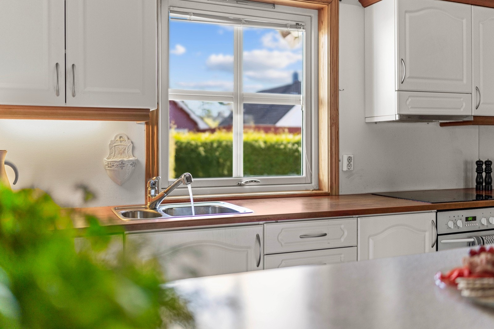 Kjøkken med gode vindusflater som slipper inn rikelig med dagslys, kombinert med praktisk kjøkkenøy og integrerte hvitevarer for en funksjonell og hyggelig arbeidsplass. Galleribilde